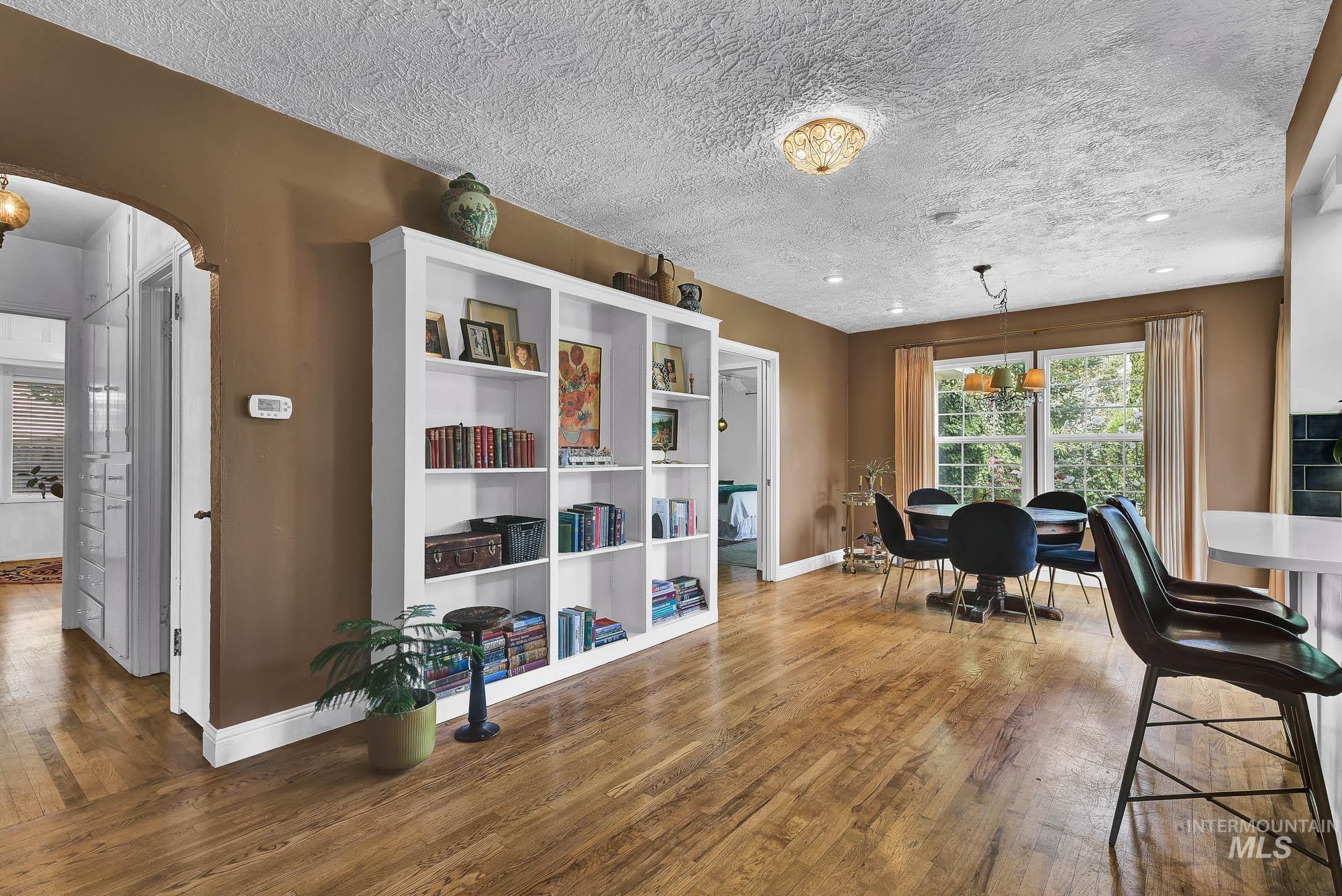 Dining area featuring wood finished floors, arched walkways and built in library area