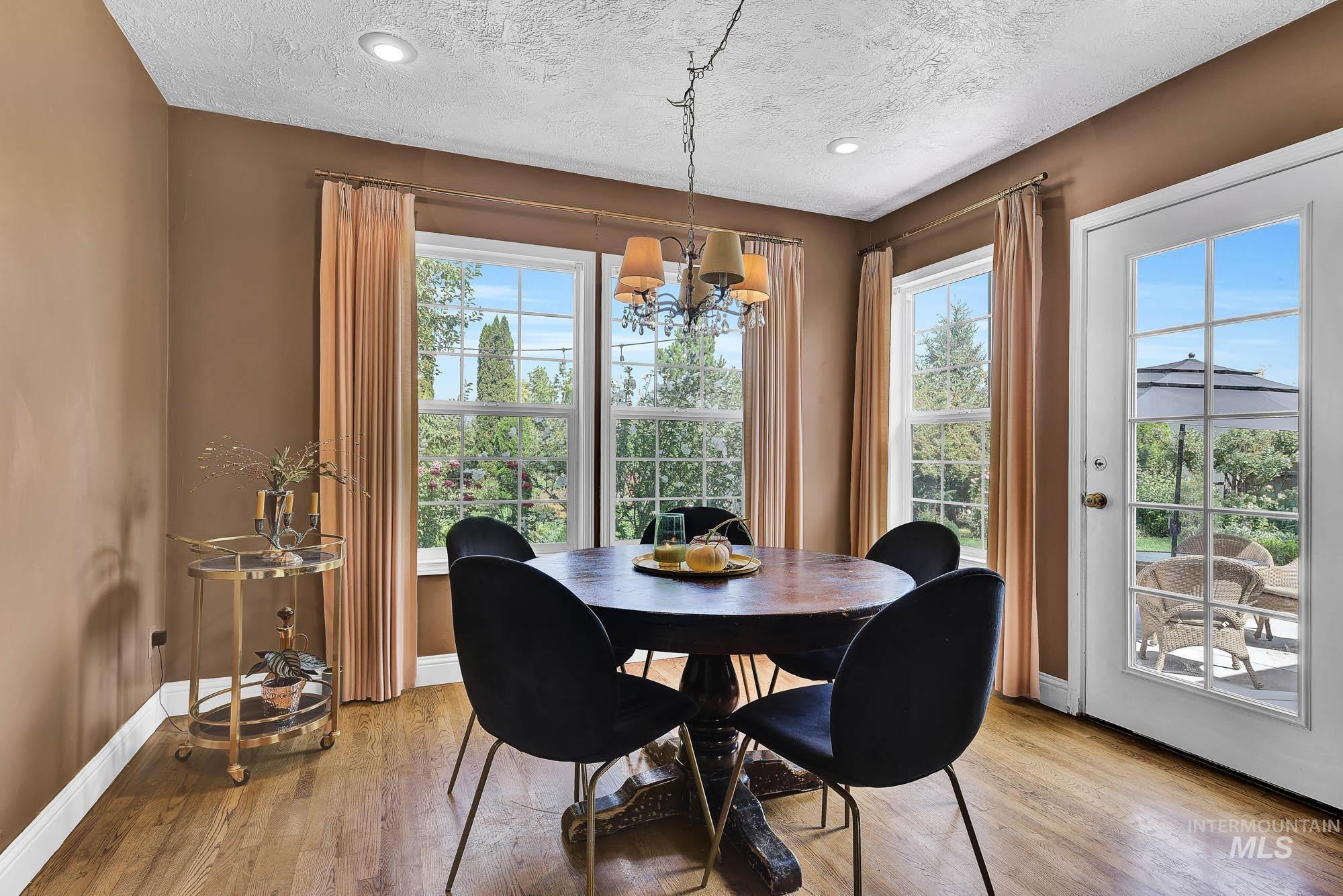 Dining room featuring a chandelier, plentiful natural light, hardwood finished floors, a textured ceiling and recessed lighting