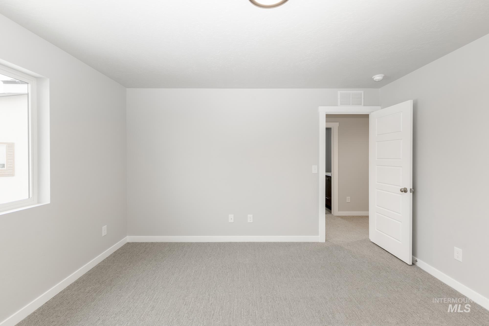 Spare room featuring light carpet and baseboards