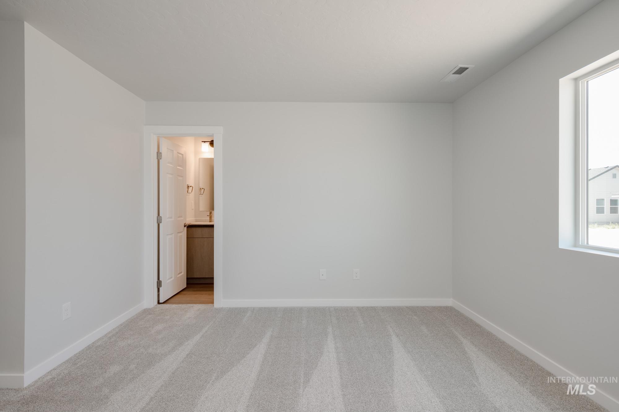 Unfurnished bedroom with light colored carpet and ensuite bathroom