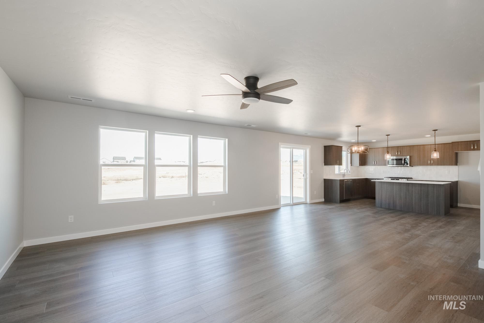 Unfurnished living room with ceiling fan and dark wood-style flooring