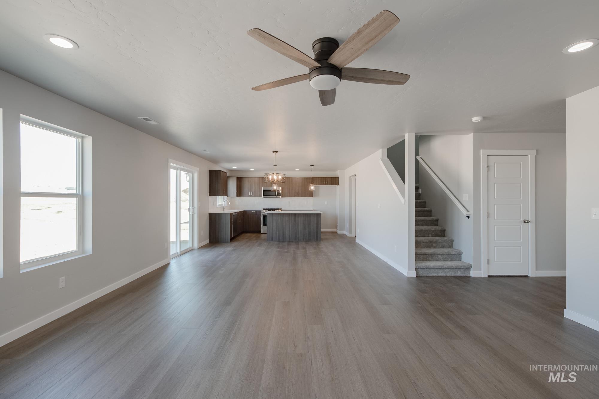 Unfurnished living room featuring recessed lighting, dark wood-style flooring, stairs, and a ceiling fan