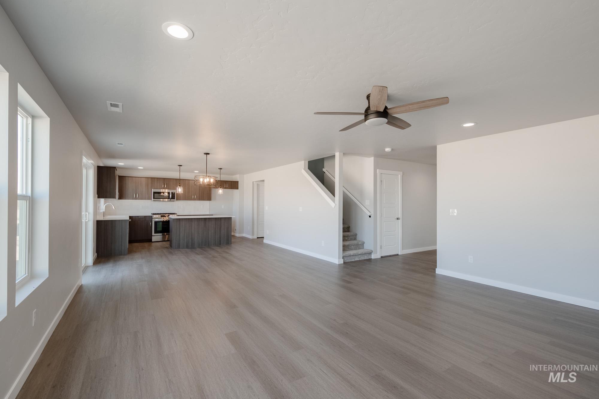 Unfurnished living room with recessed lighting, dark wood-type flooring, stairs, and a ceiling fan