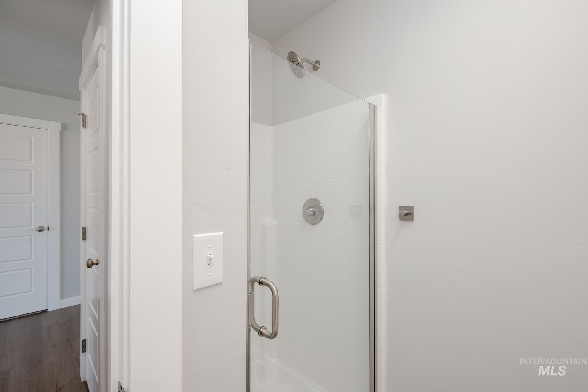 Full bath featuring a shower stall and dark wood-style floors