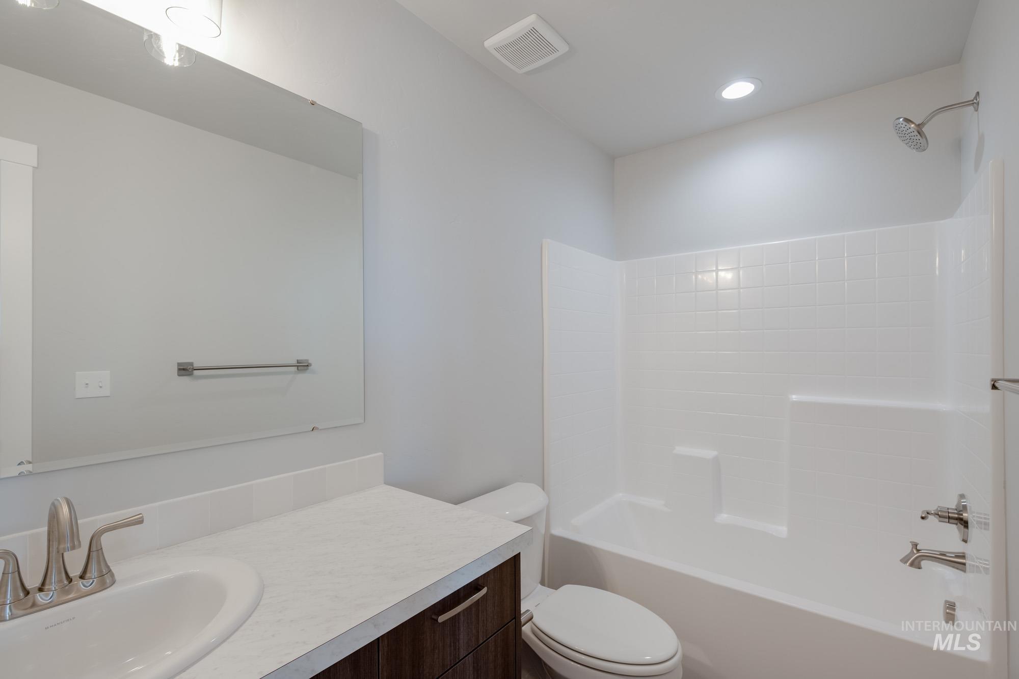 Bathroom with bathtub / shower combination, vanity, and recessed lighting