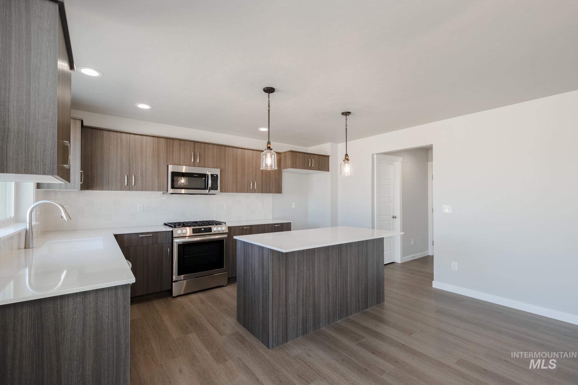 Kitchen with appliances with stainless steel finishes, modern cabinets, dark wood-style flooring, decorative light fixtures, and recessed lighting
