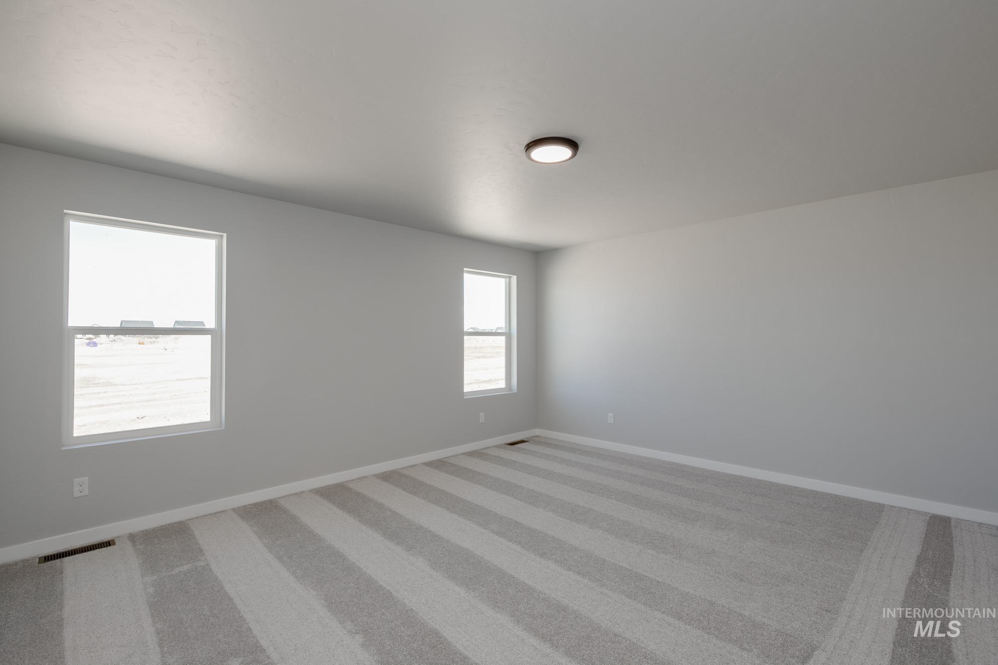 Empty room with light colored carpet and baseboards