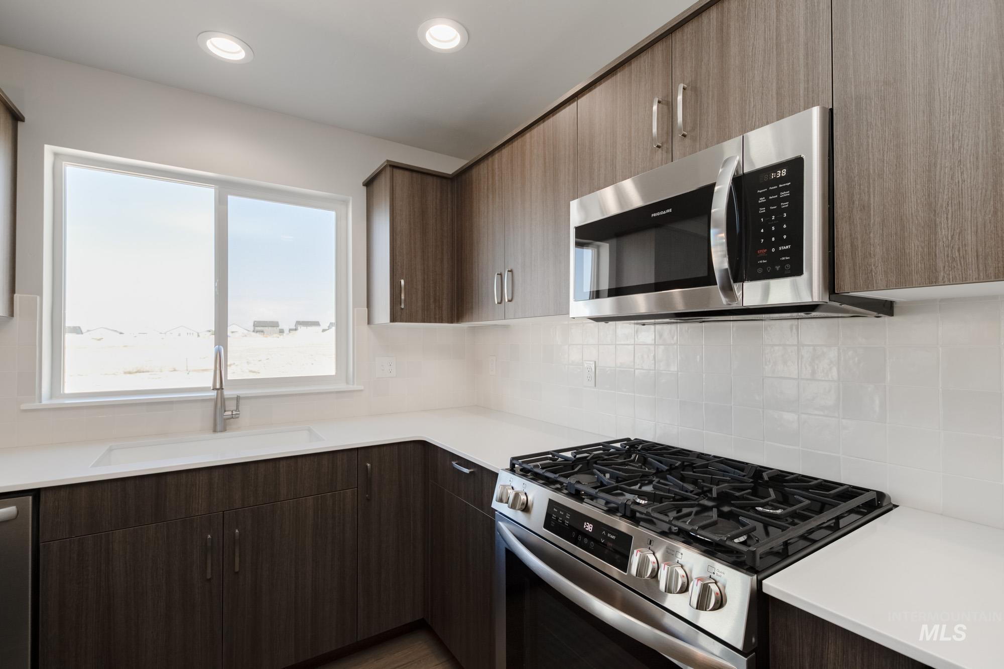 Kitchen featuring appliances with stainless steel finishes, modern cabinets, tasteful backsplash, recessed lighting, and dark brown cabinets