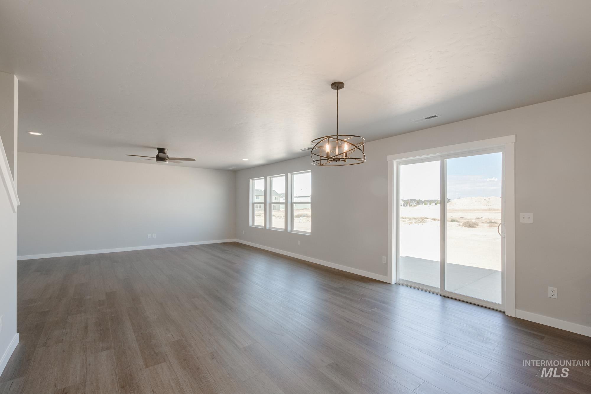 Empty room with light wood-style flooring, ceiling fan, and a chandelier