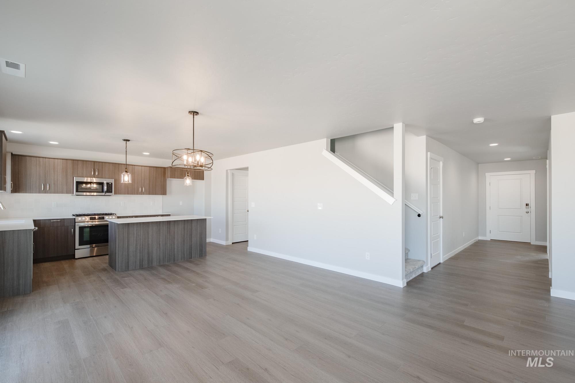 Kitchen featuring recessed lighting, light countertops, light wood-style floors, decorative light fixtures, and stainless steel appliances