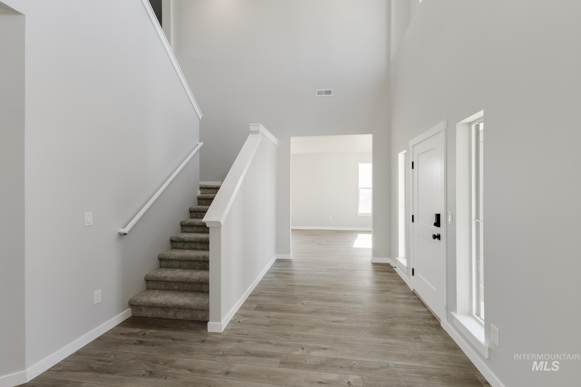Entryway with stairway, light wood finished floors, and a high ceiling
