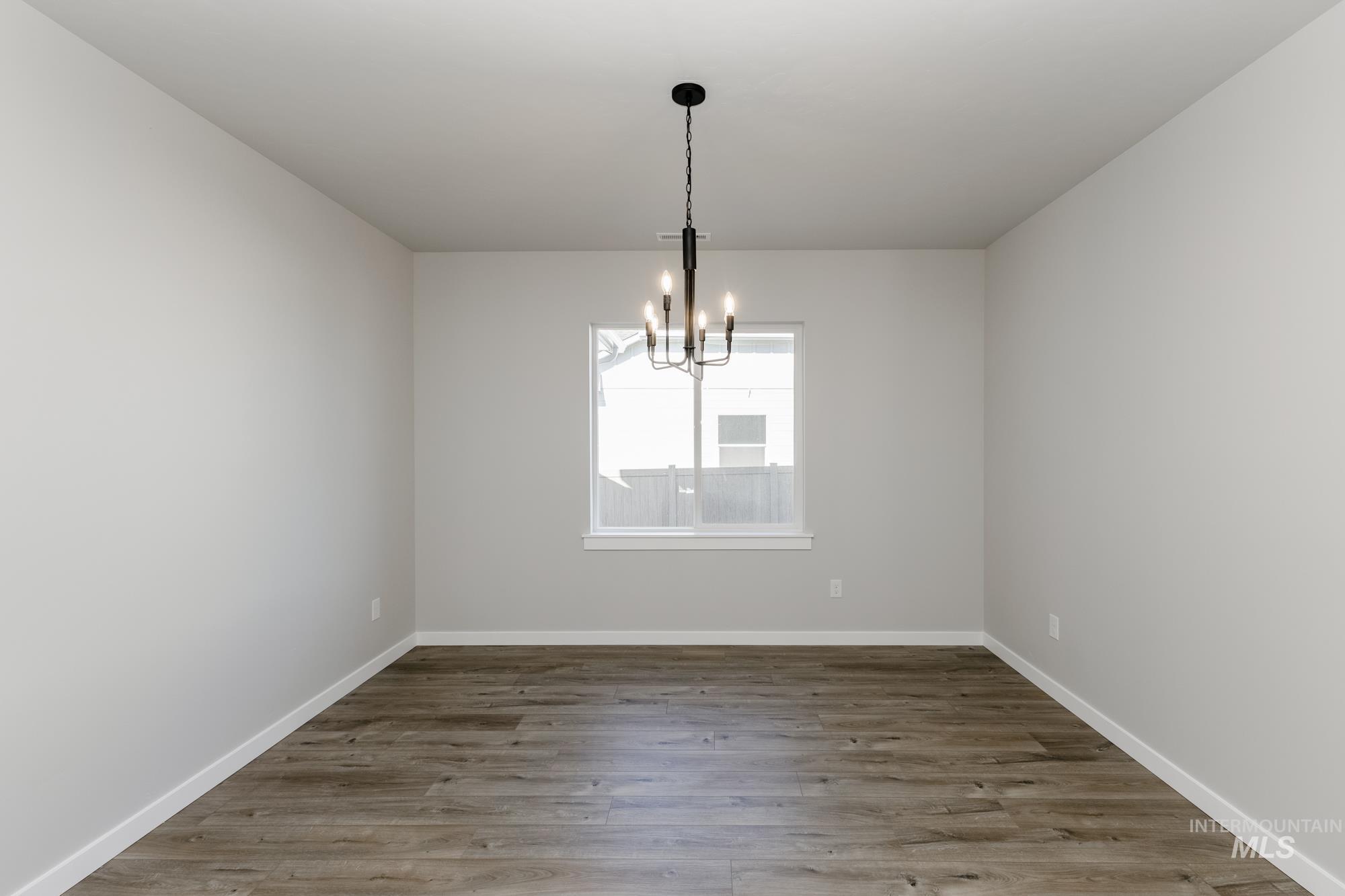 Spare room with light wood finished floors and a chandelier