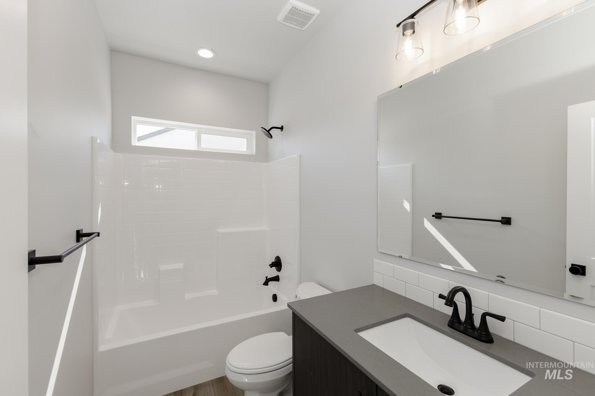 Bathroom with shower / bathtub combination, vanity, and backsplash