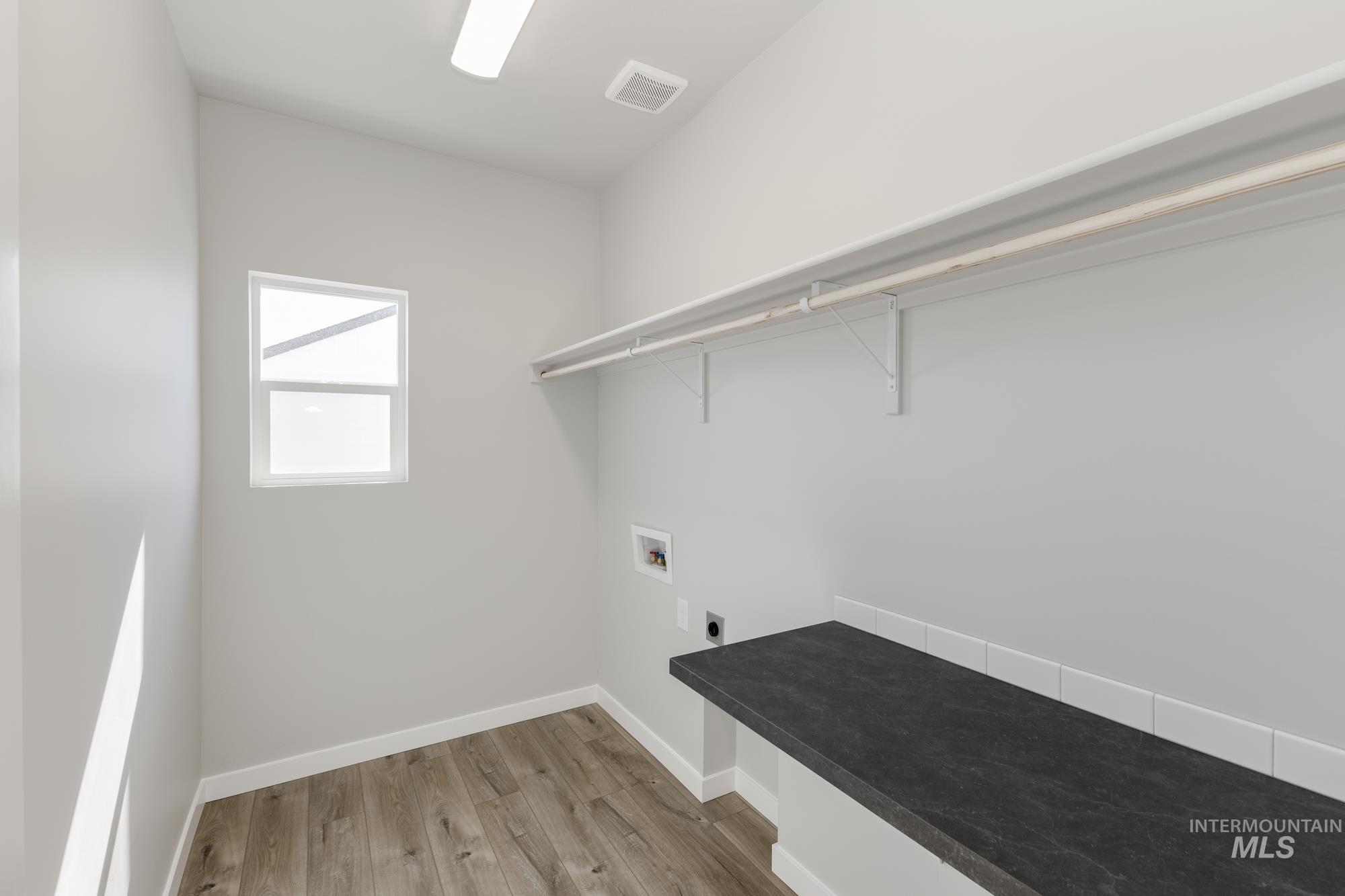 Laundry area with washer hookup, light wood-type flooring, and electric dryer hookup