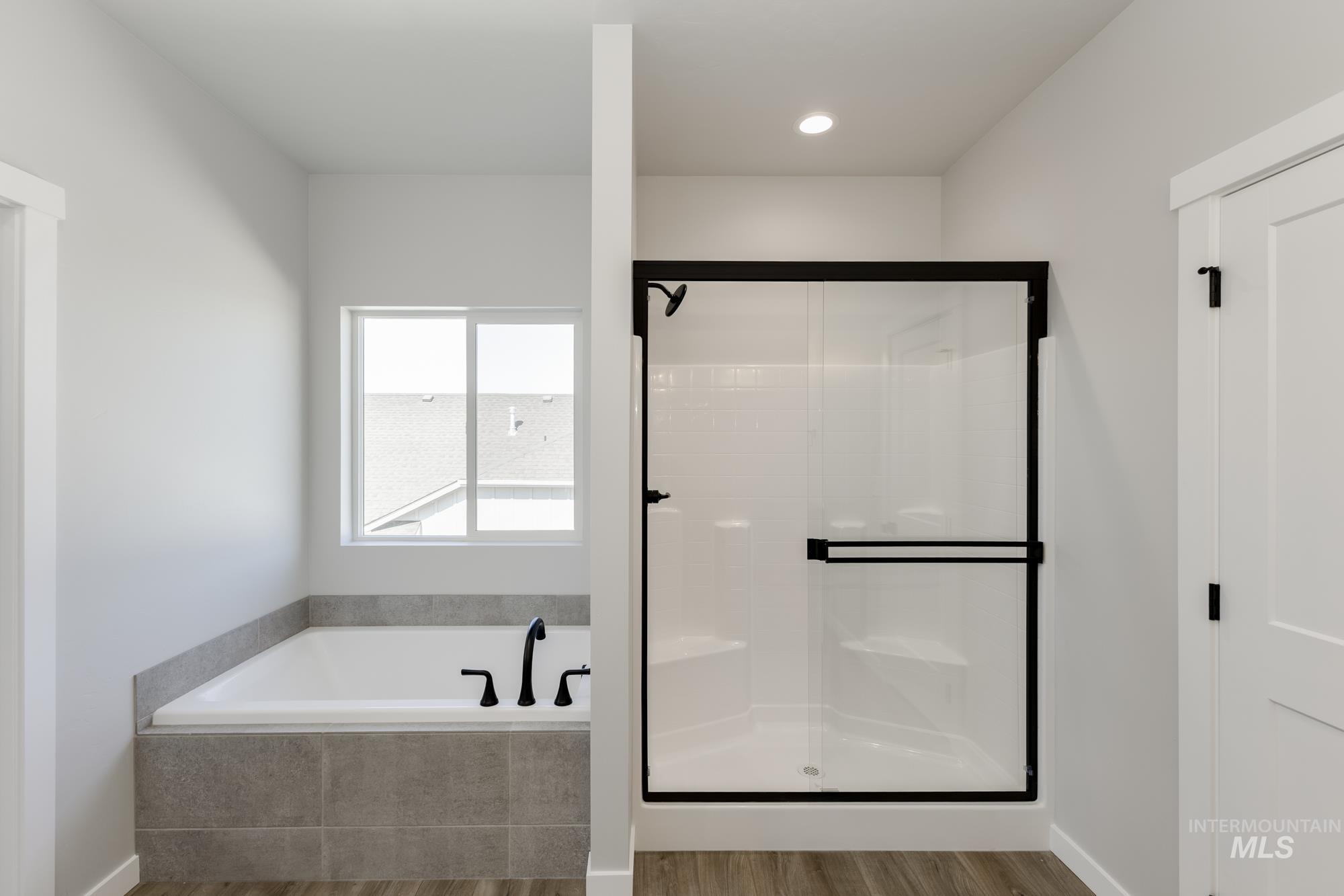 Bathroom featuring wood finished floors, a stall shower, a bath, and recessed lighting