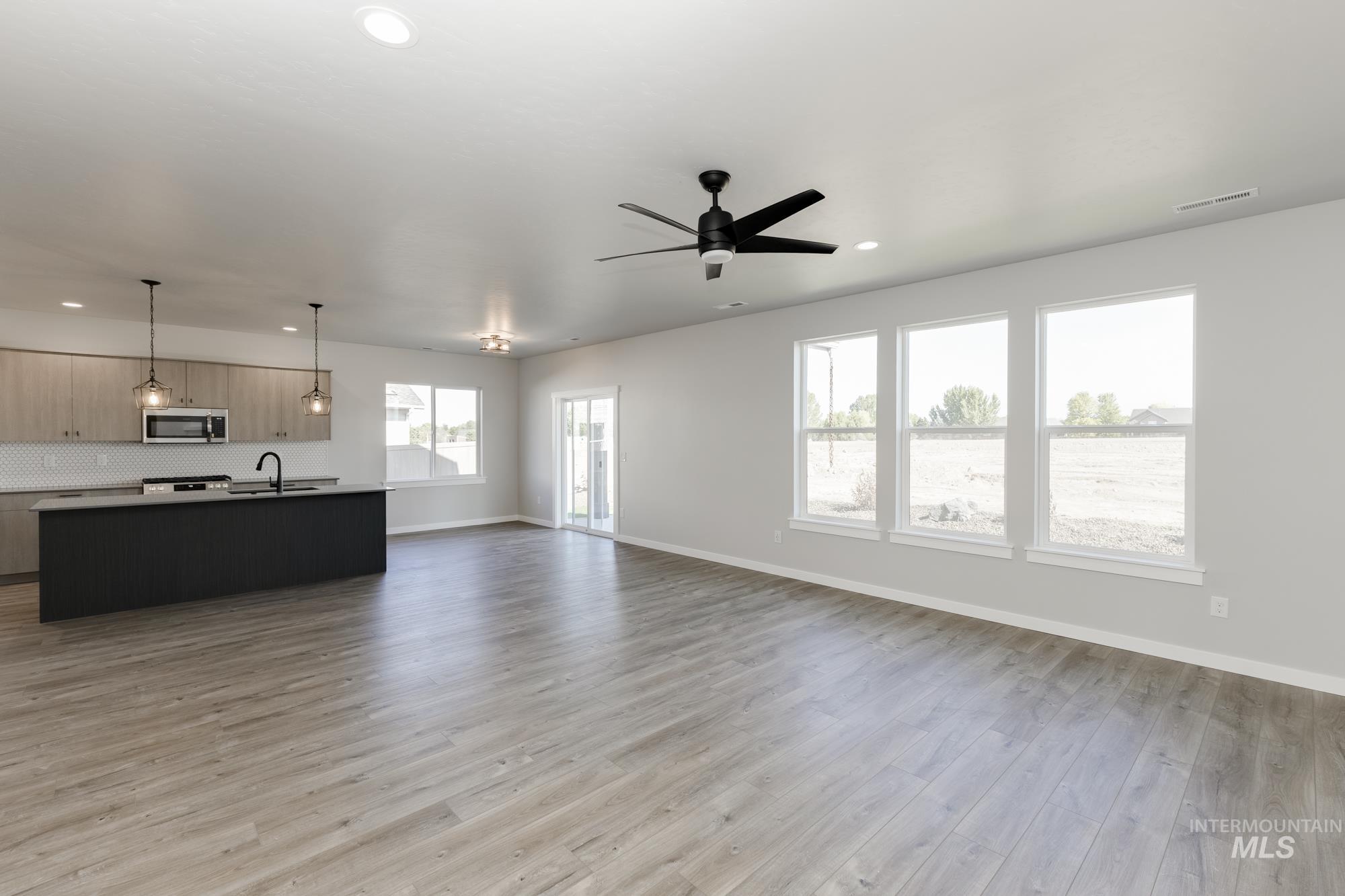 Unfurnished living room with light wood-type flooring, a ceiling fan, and recessed lighting