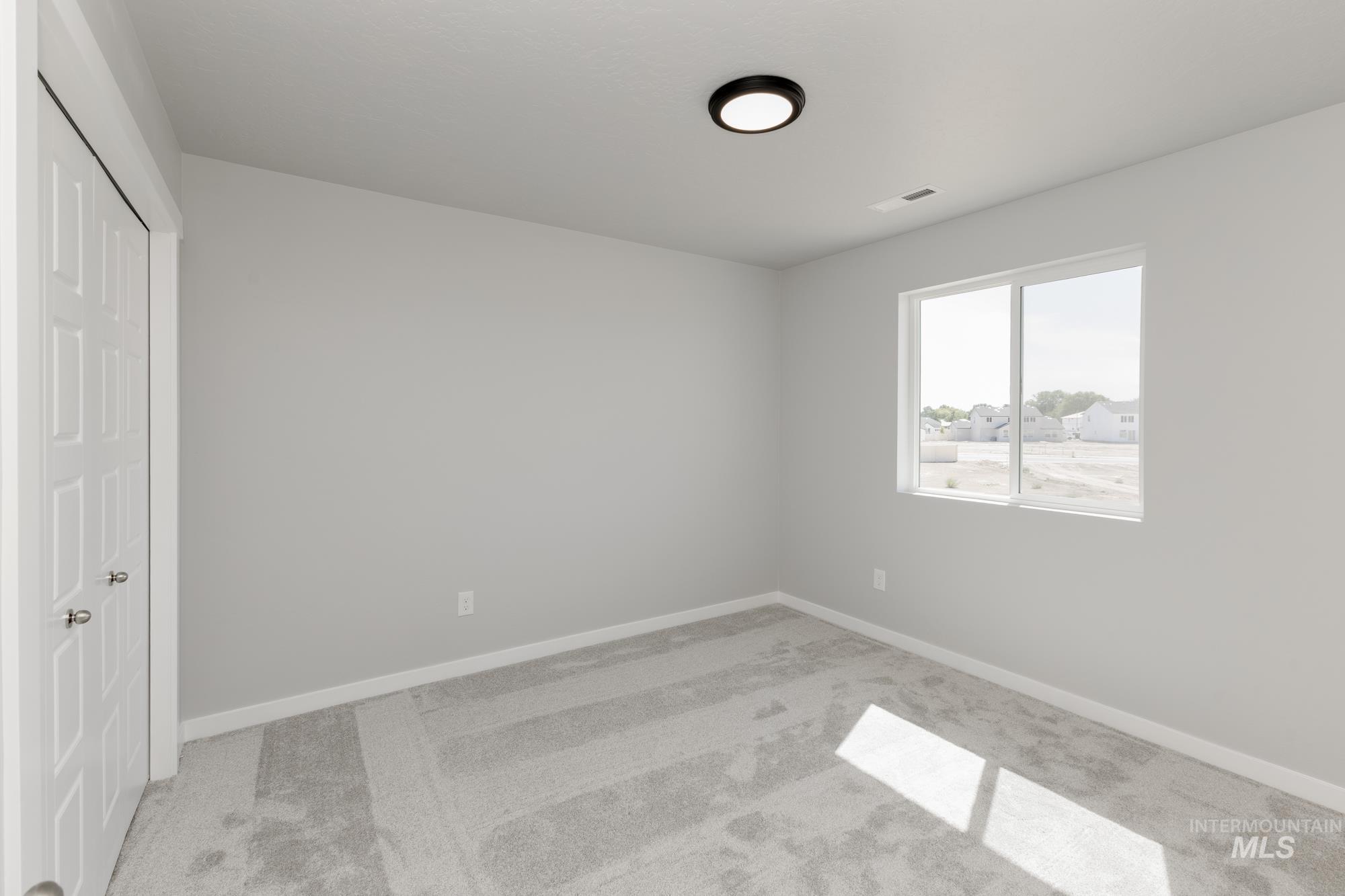 Unfurnished bedroom with light colored carpet and baseboards