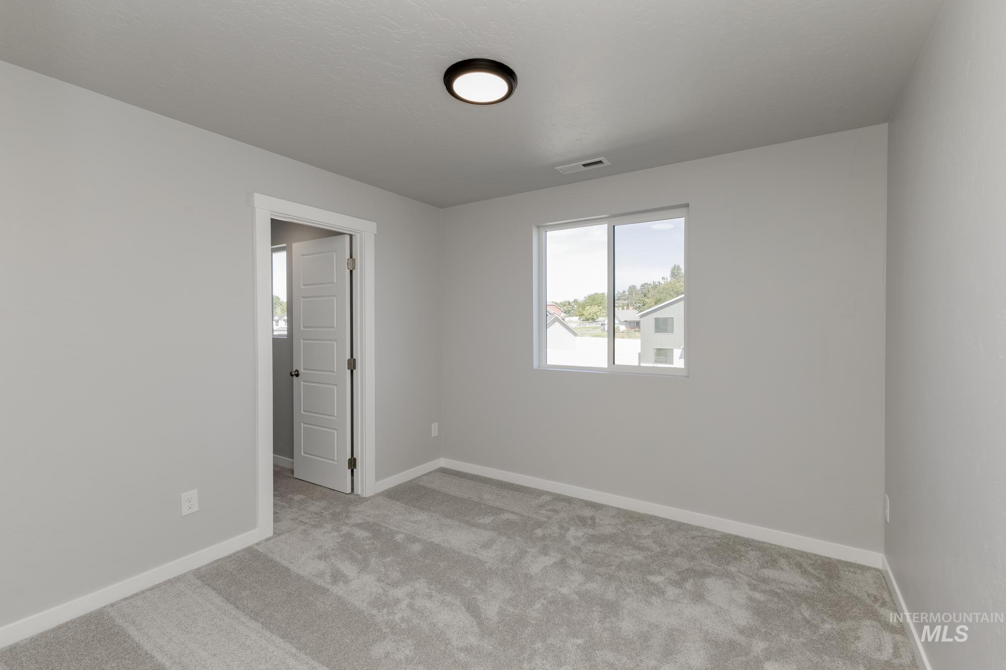 Carpeted spare room featuring baseboards
