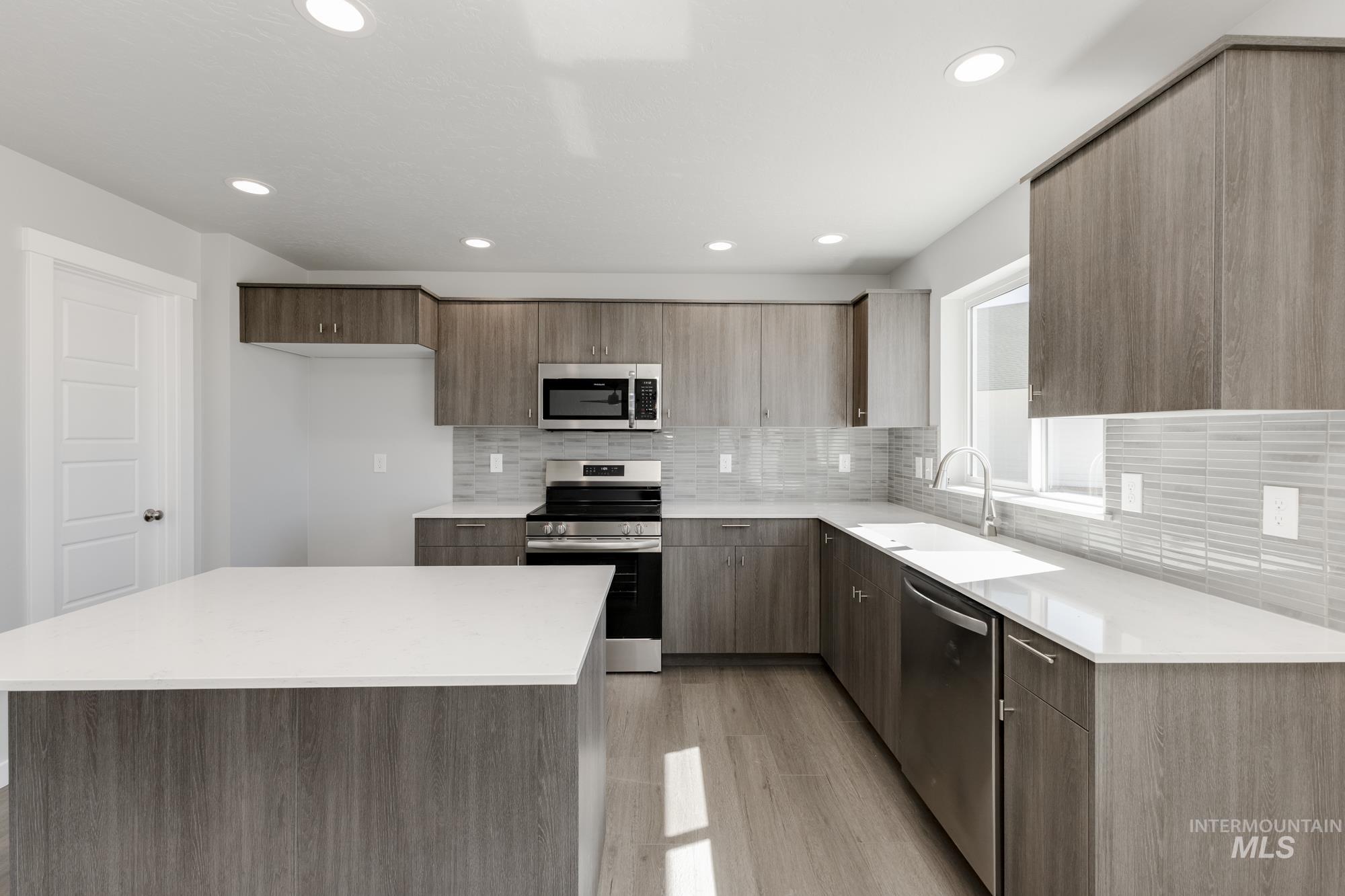 Kitchen with a center island, tasteful backsplash, stainless steel appliances, modern cabinets, and light wood-style floors