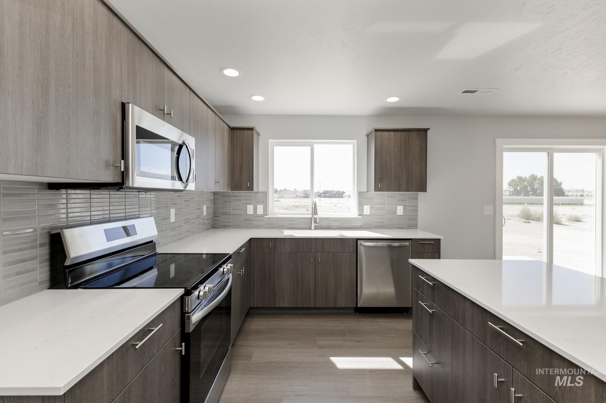 Kitchen with stainless steel appliances, backsplash, light wood-style flooring, dark brown cabinets, and recessed lighting