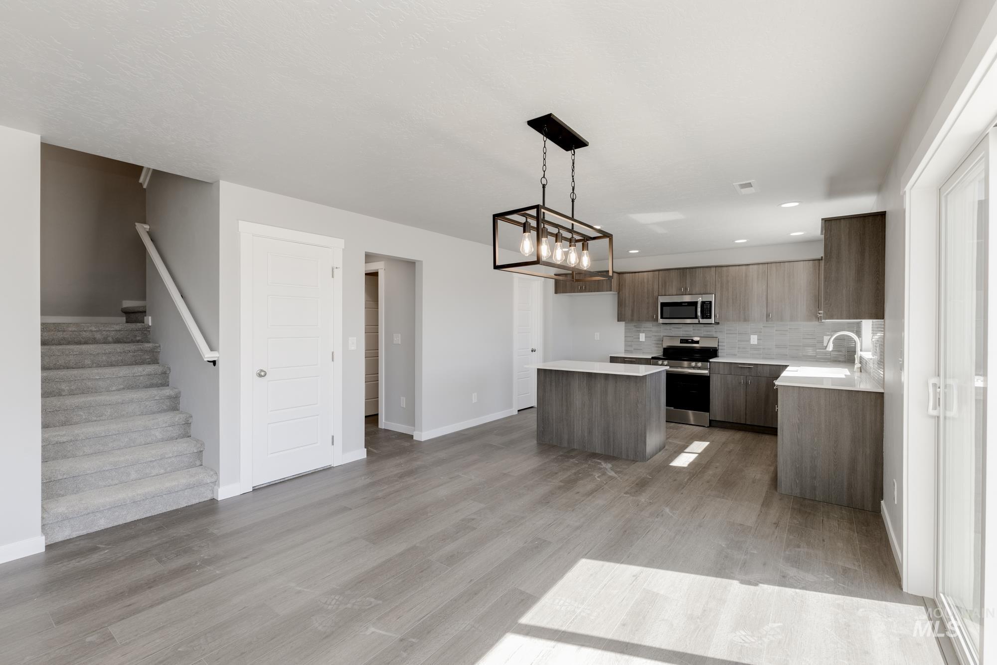 Kitchen featuring modern cabinets, backsplash, appliances with stainless steel finishes, a kitchen island, and a chandelier