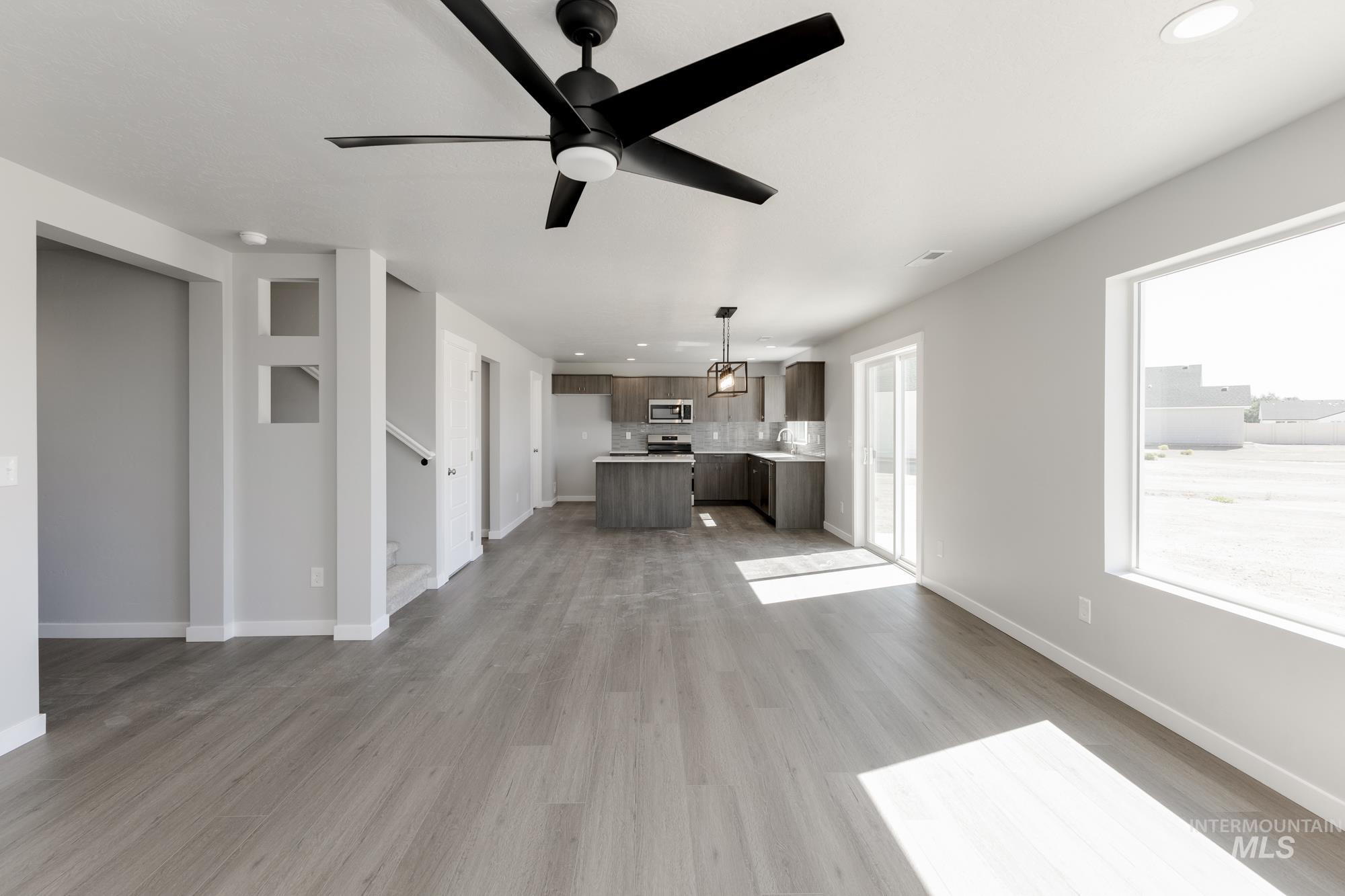 Unfurnished living room featuring light wood finished floors, a ceiling fan, recessed lighting, and stairs