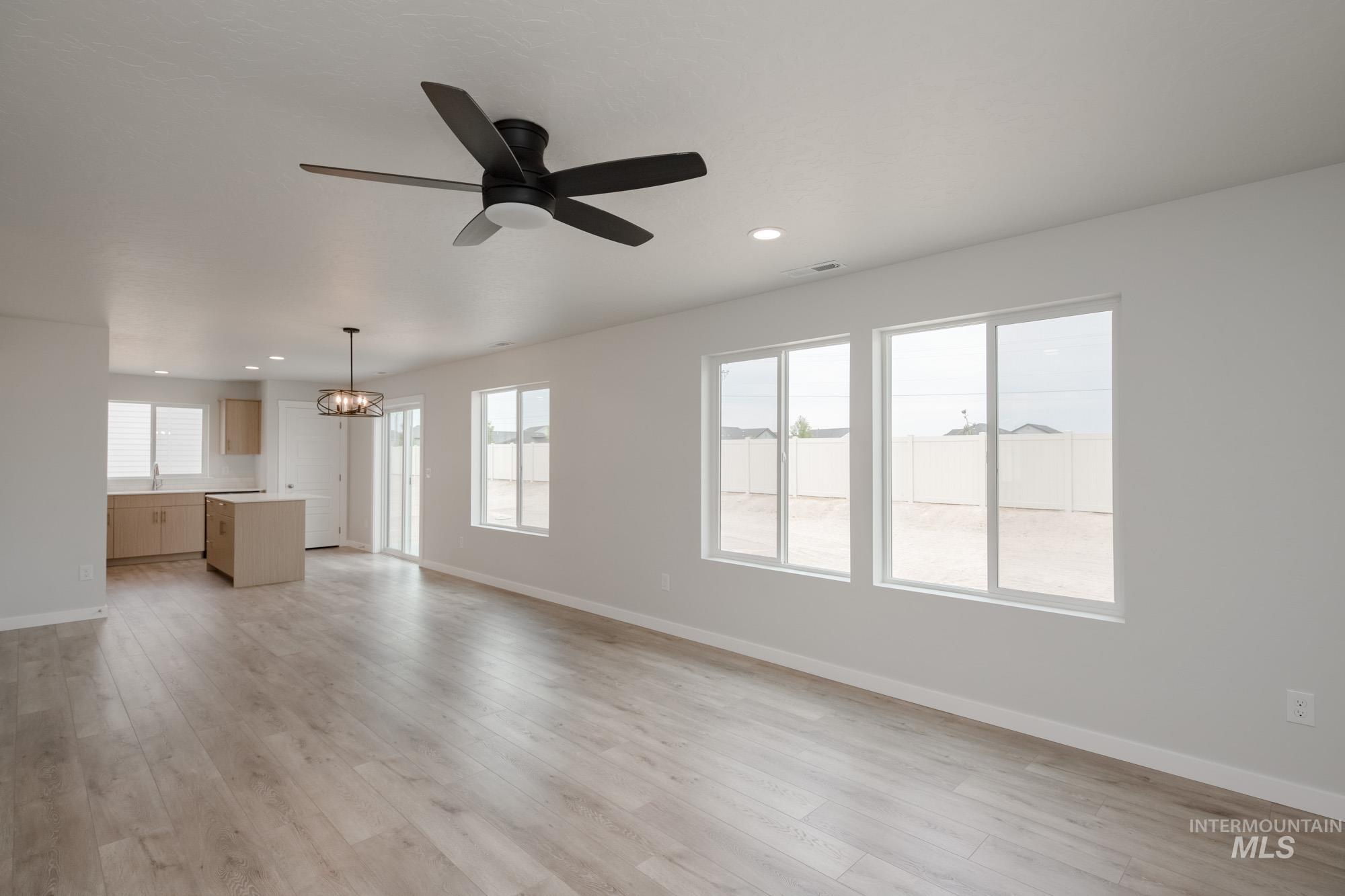 Unfurnished living room with light wood finished floors, a chandelier, a ceiling fan, and recessed lighting