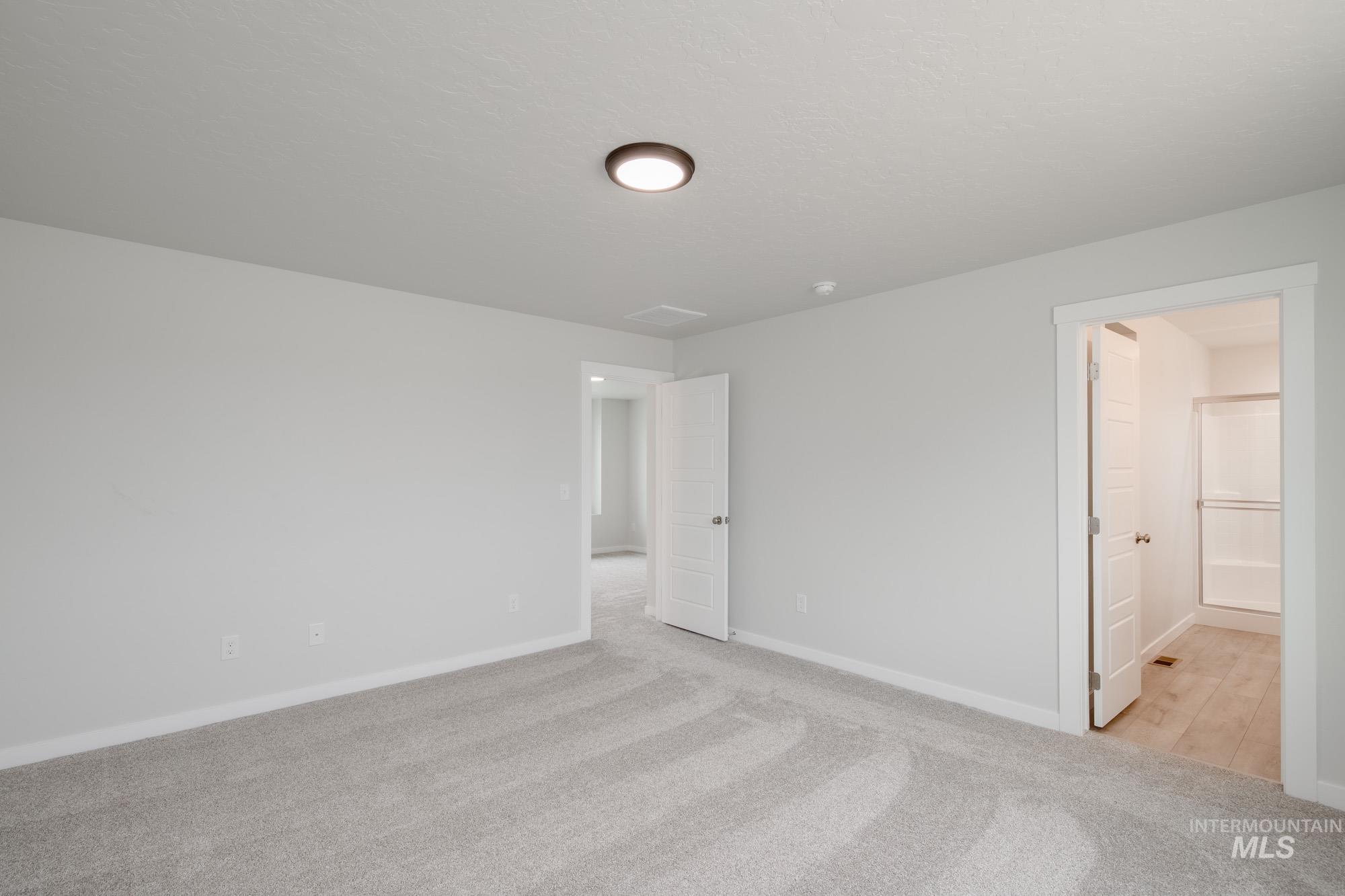 Unfurnished bedroom with light colored carpet and ensuite bathroom