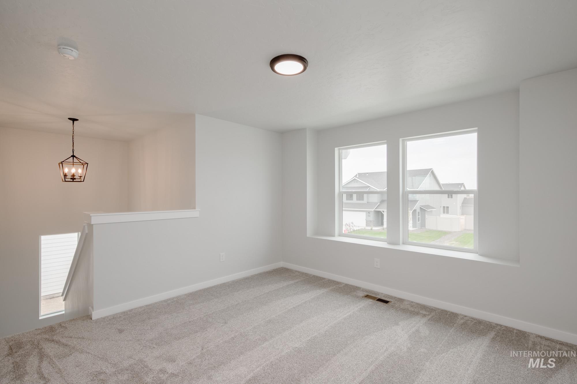 Spare room featuring light carpet and a chandelier