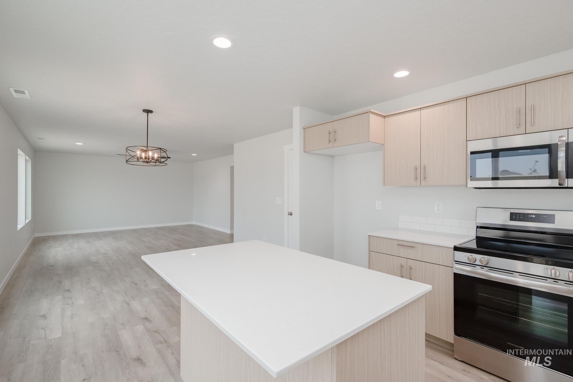 Kitchen featuring stainless steel appliances, light brown cabinetry, recessed lighting, a center island, and light wood finished floors