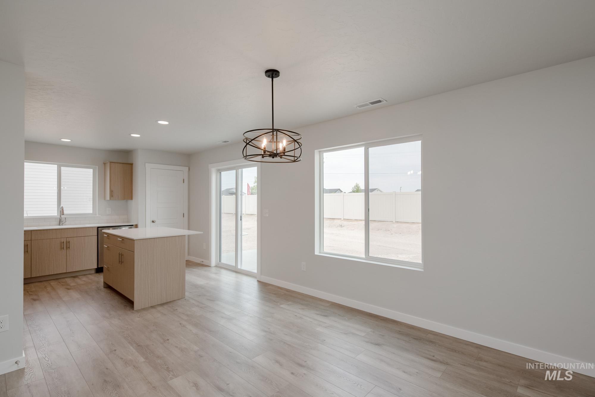 Kitchen with pendant lighting, a center island, light brown cabinets, light countertops, and light wood-style flooring