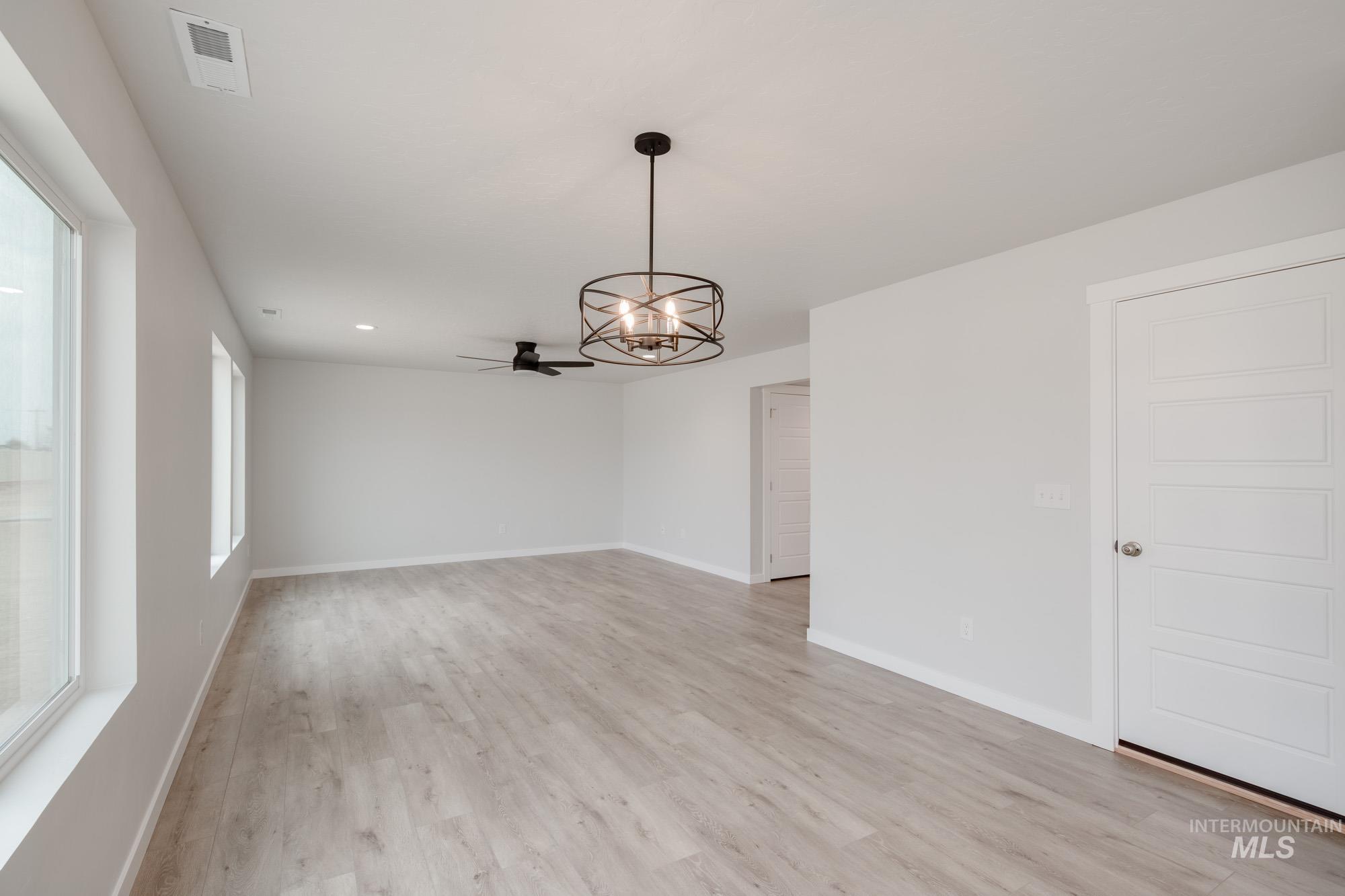 Empty room featuring a chandelier, light wood-style floors, a ceiling fan, and recessed lighting