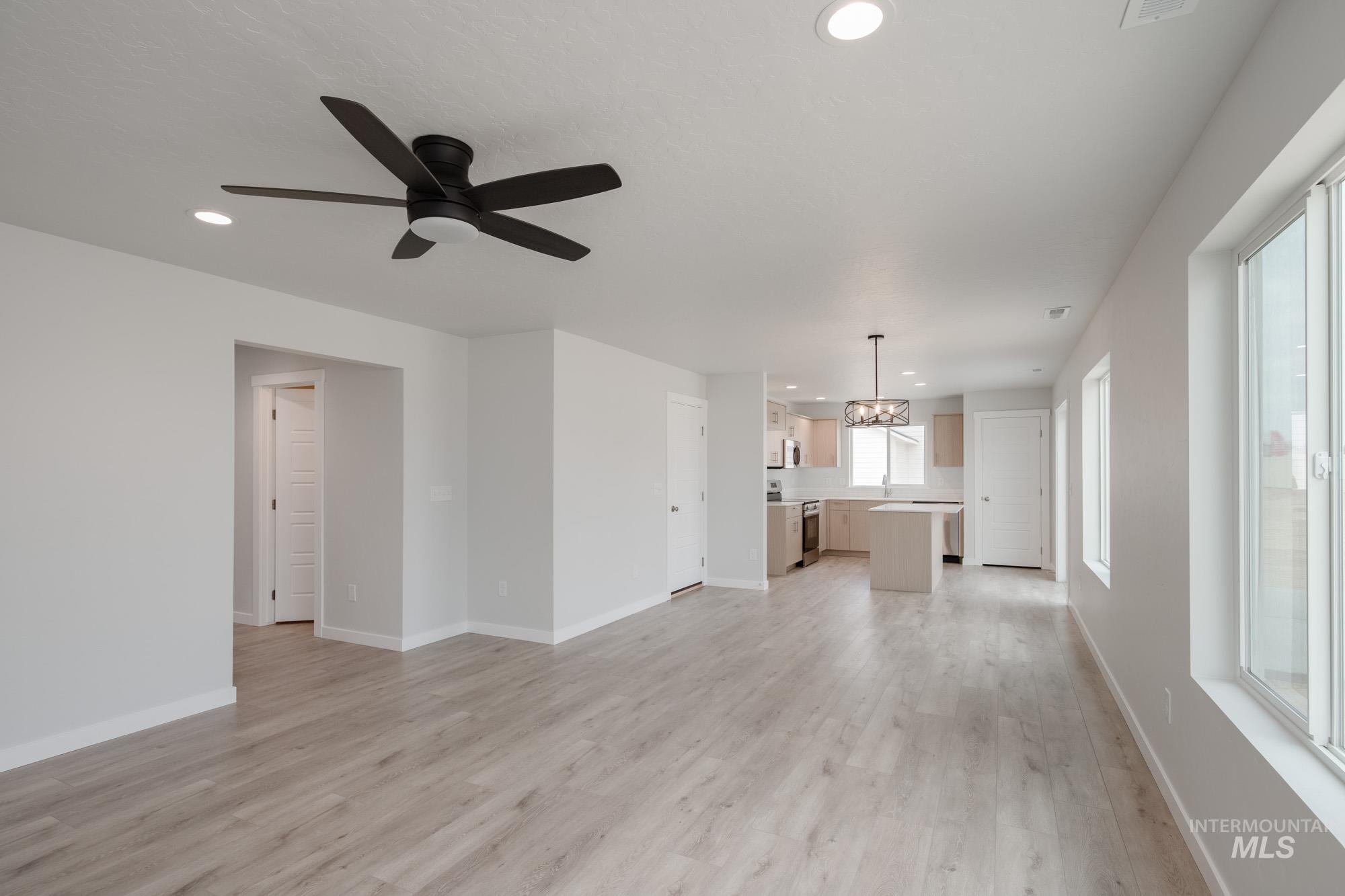 Unfurnished living room featuring recessed lighting, light wood-style flooring, a chandelier, and a ceiling fan