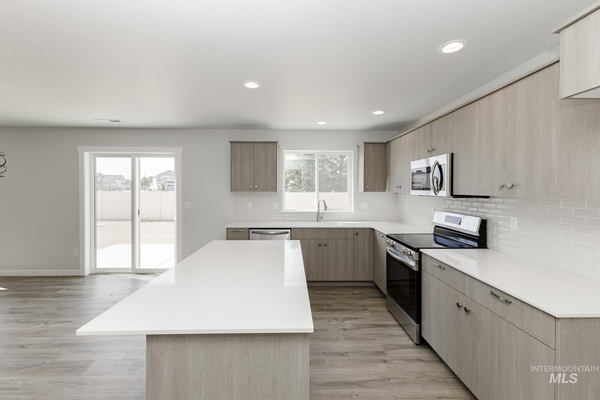 Kitchen featuring appliances with stainless steel finishes, healthy amount of natural light, tasteful backsplash, light countertops, and recessed lighting