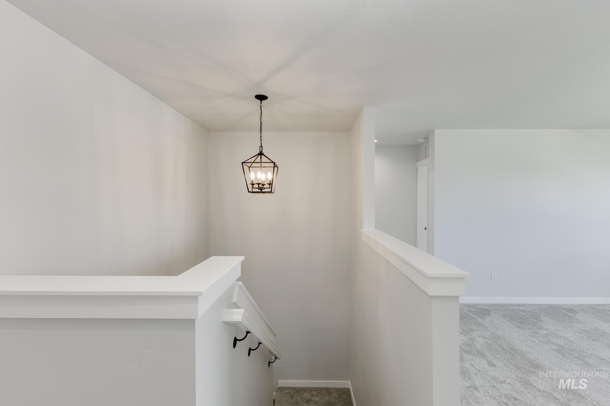 Stairway with carpet floors and a chandelier