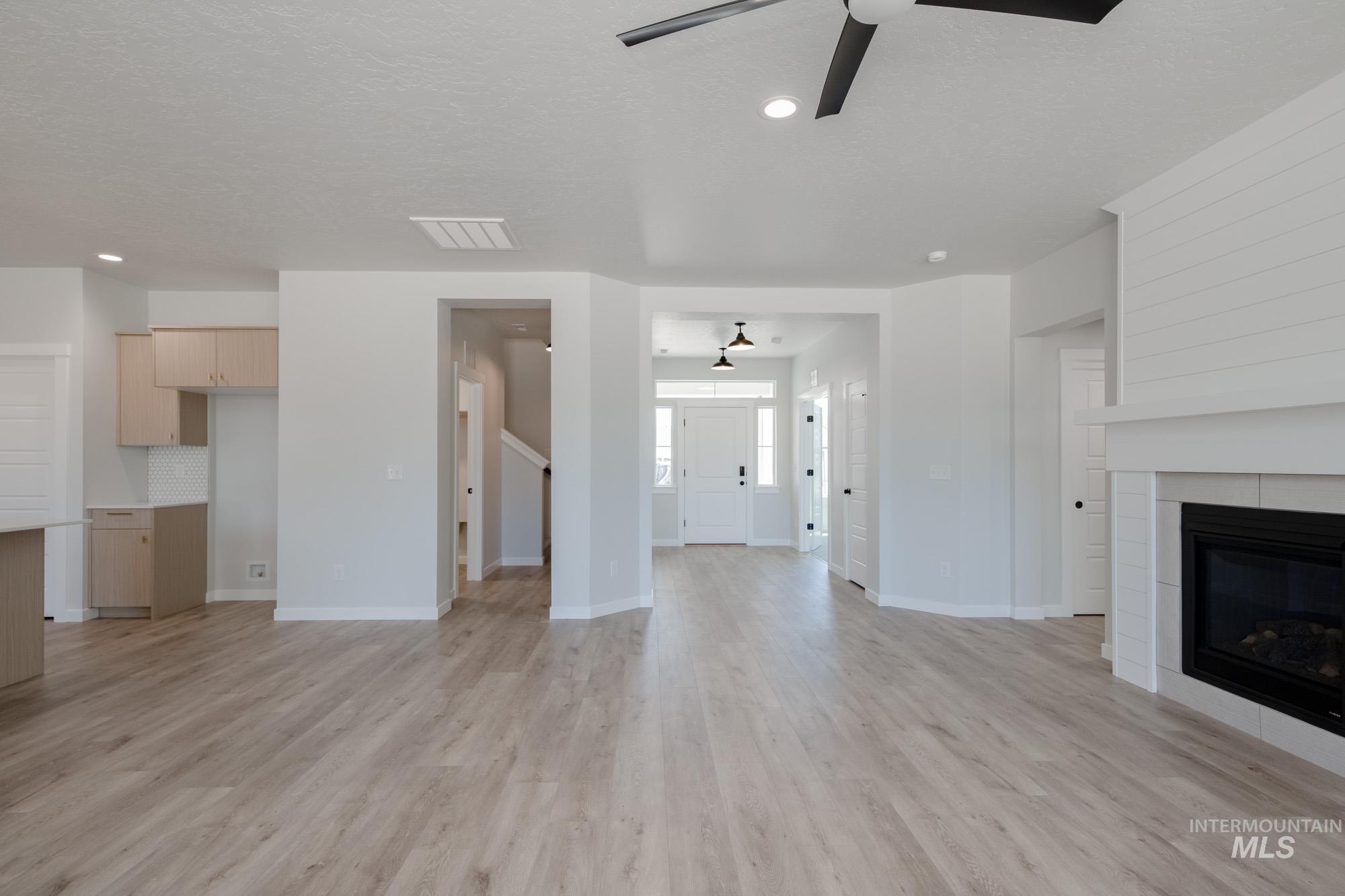 Unfurnished living room with light wood-style flooring, a tile fireplace, recessed lighting, a ceiling fan, and a textured ceiling