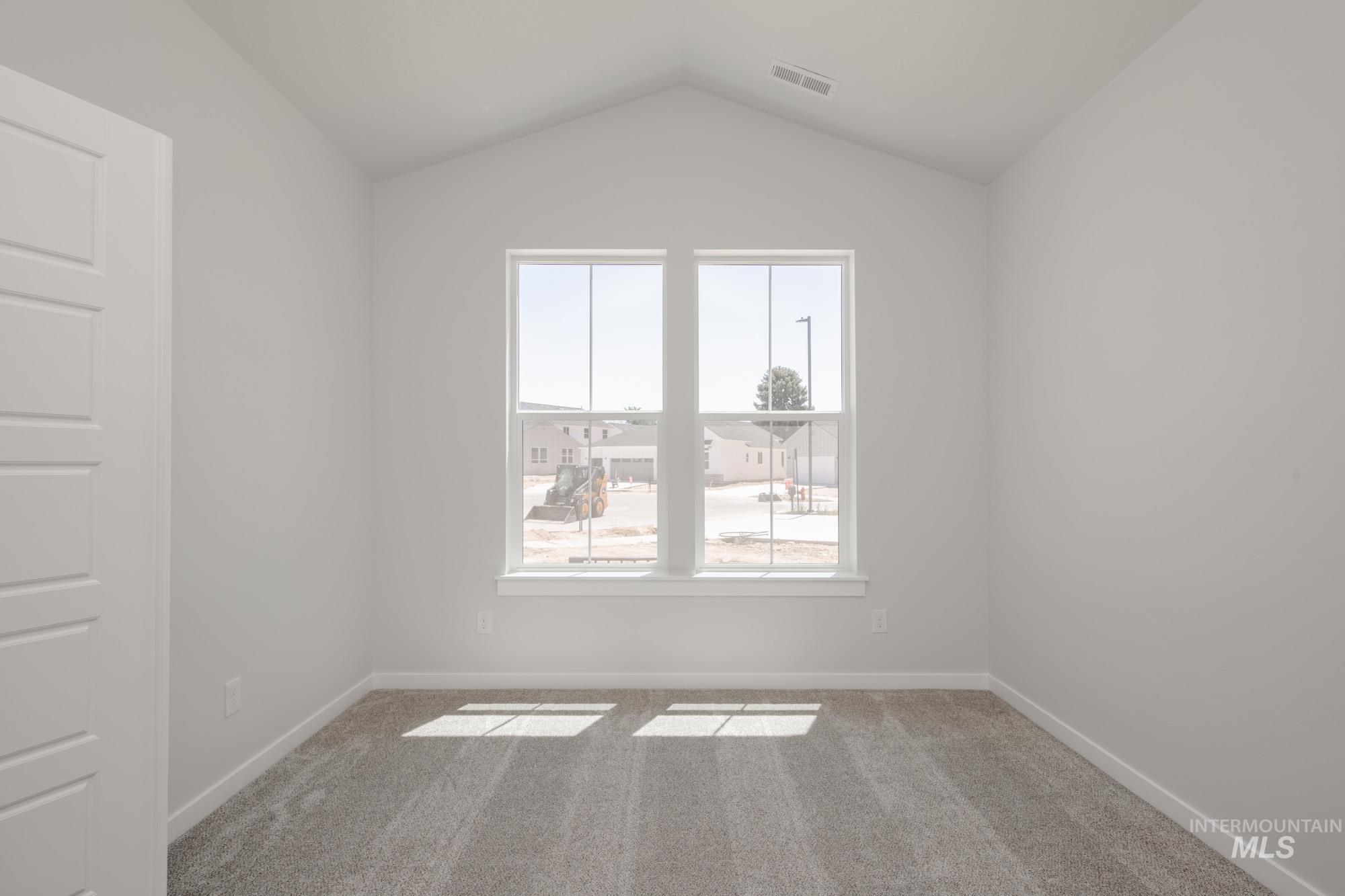 Empty room featuring carpet flooring and lofted ceiling