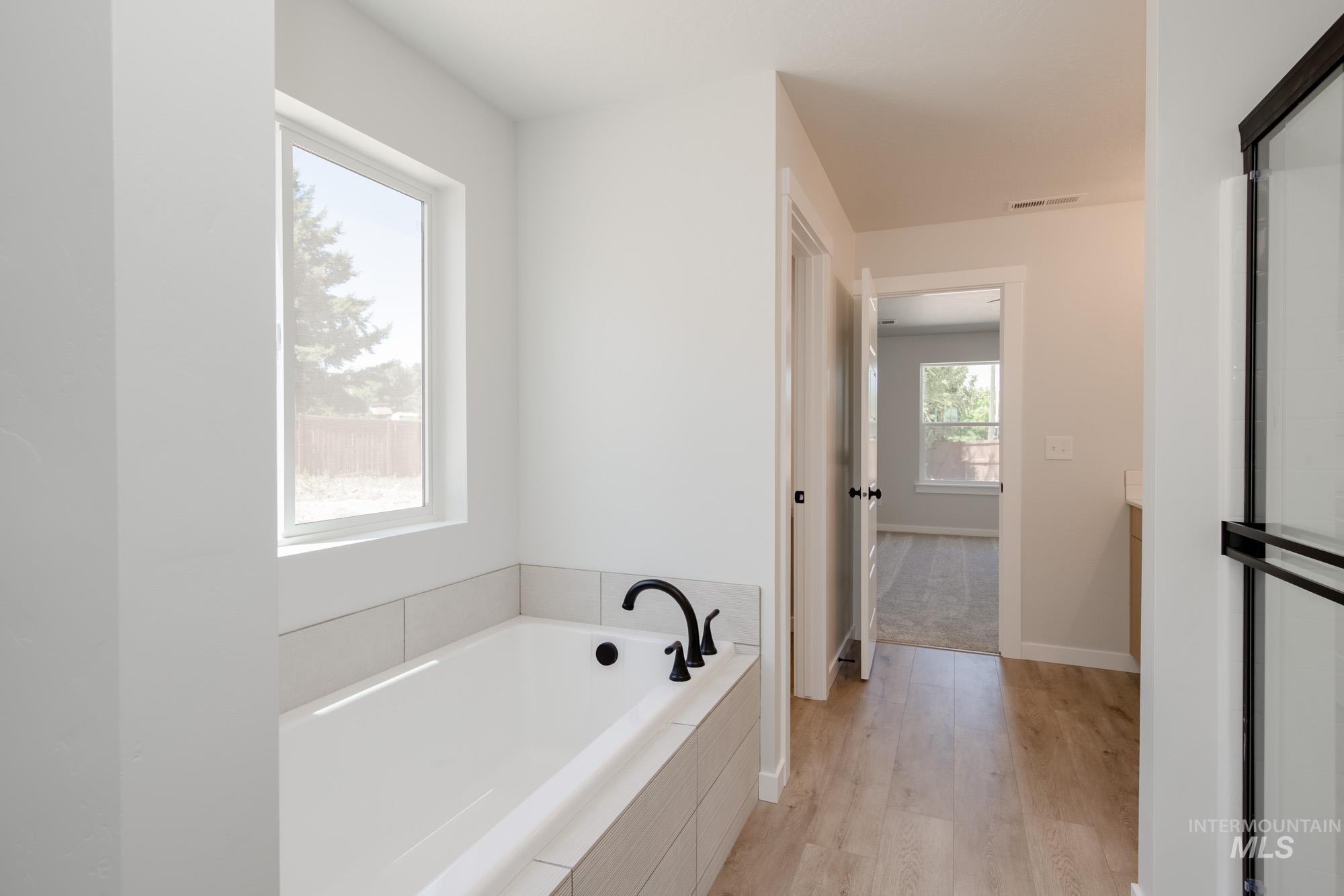 Bathroom with a garden tub, vanity, and light wood-style flooring