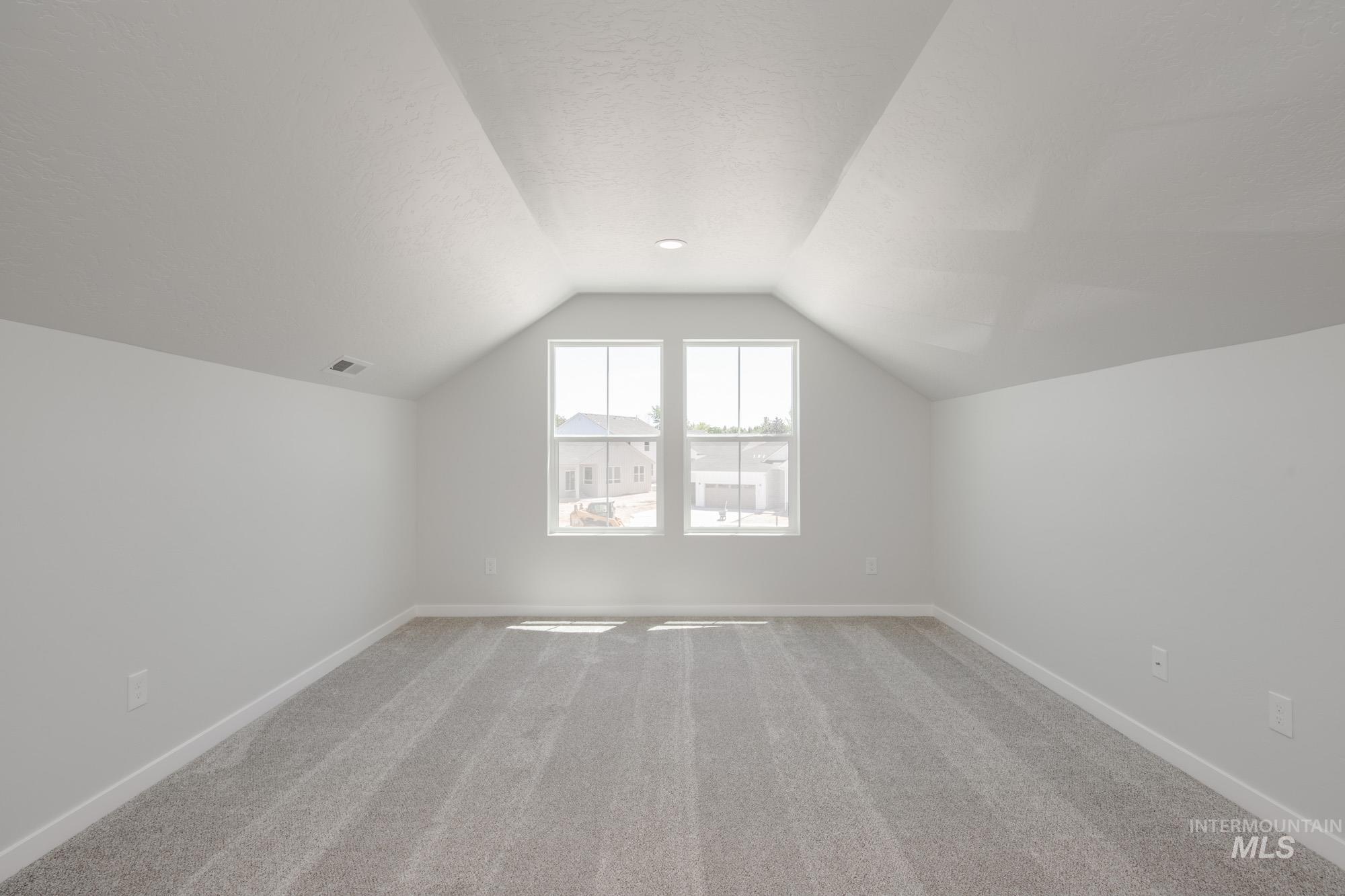 Bonus room with carpet flooring, vaulted ceiling, and a textured ceiling