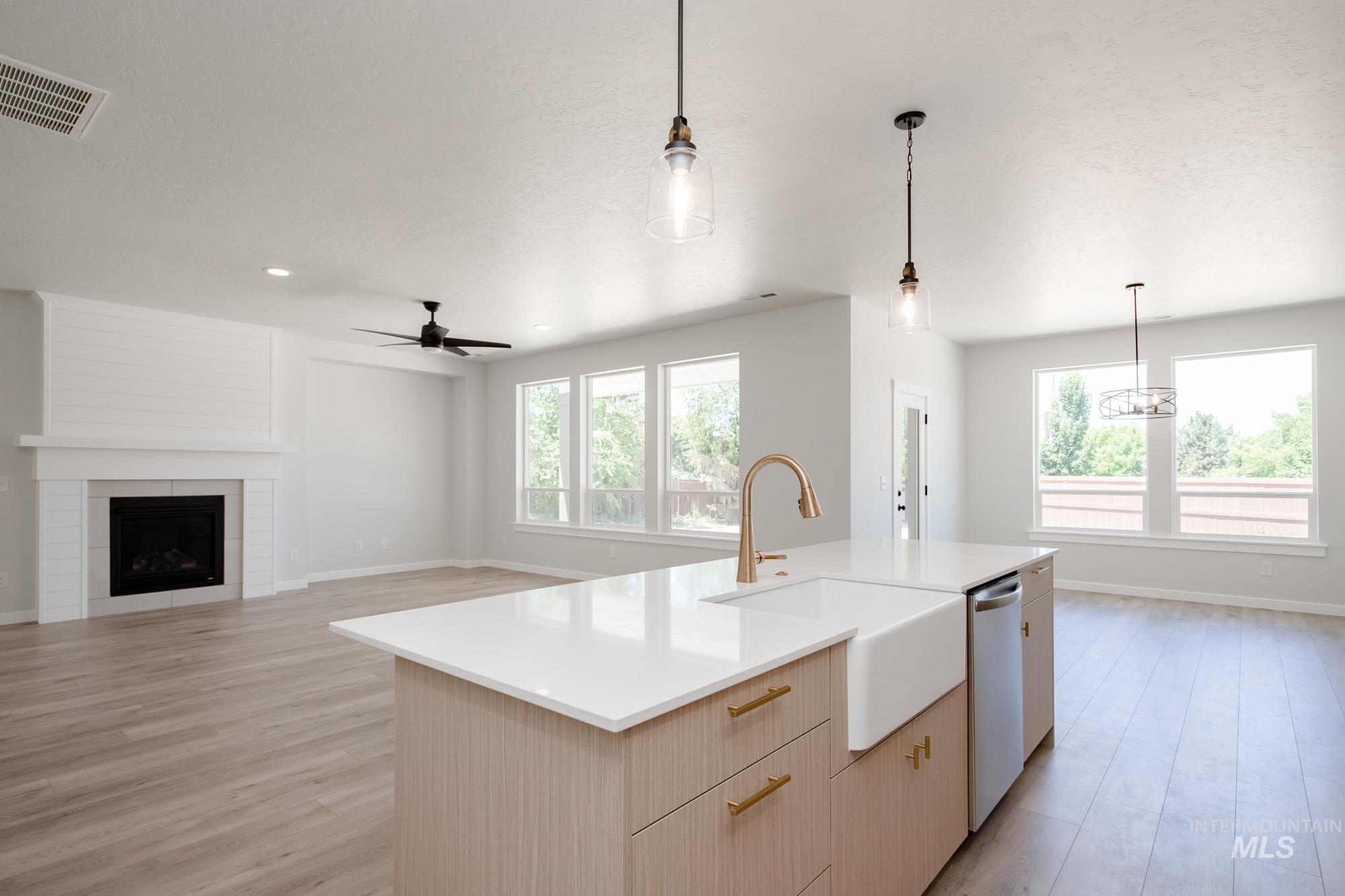 Kitchen featuring light brown cabinetry, pendant lighting, light wood-style floors, modern cabinets, and a kitchen island with sink