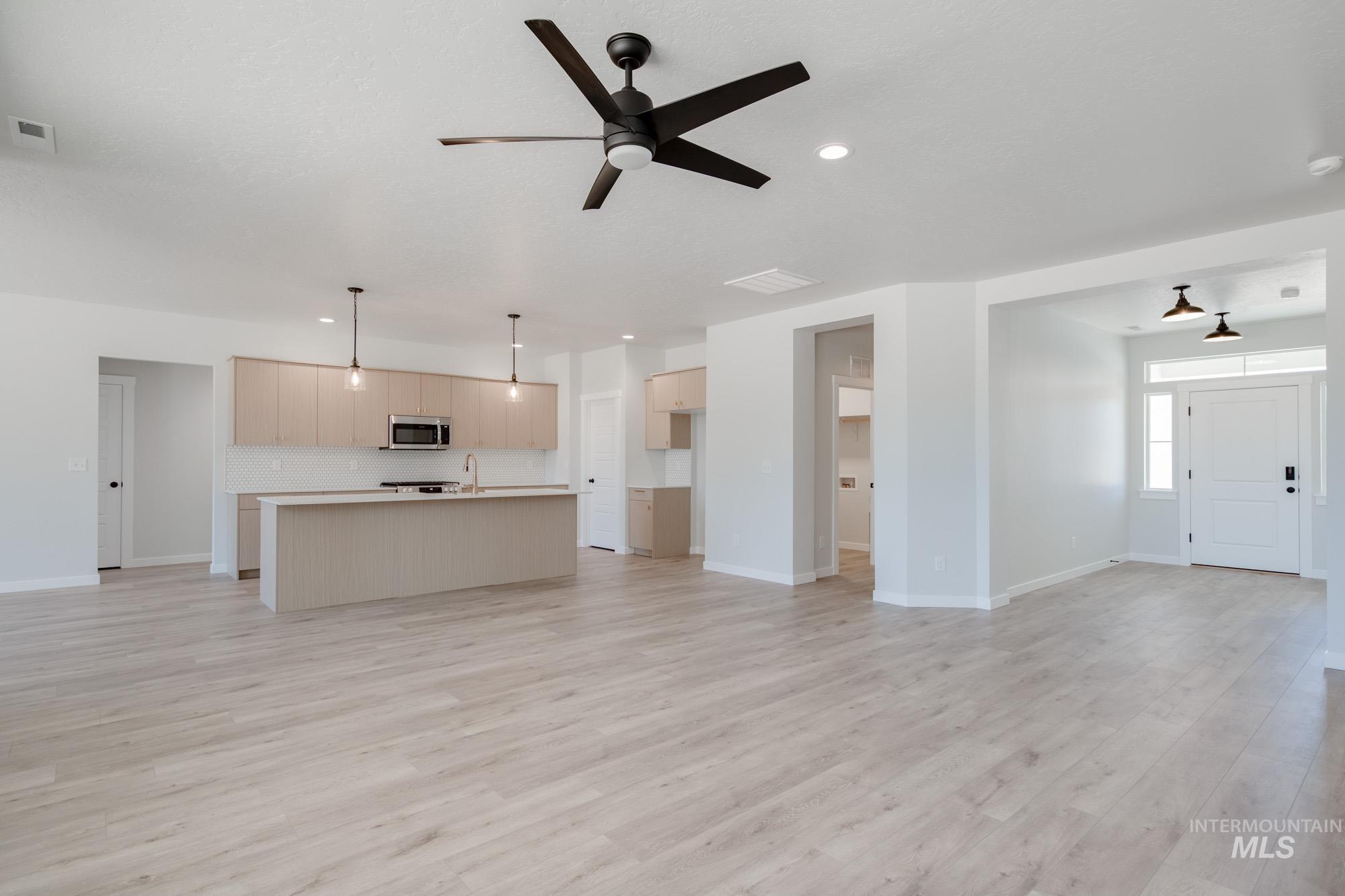 Unfurnished living room with light wood-style floors, a ceiling fan, and recessed lighting