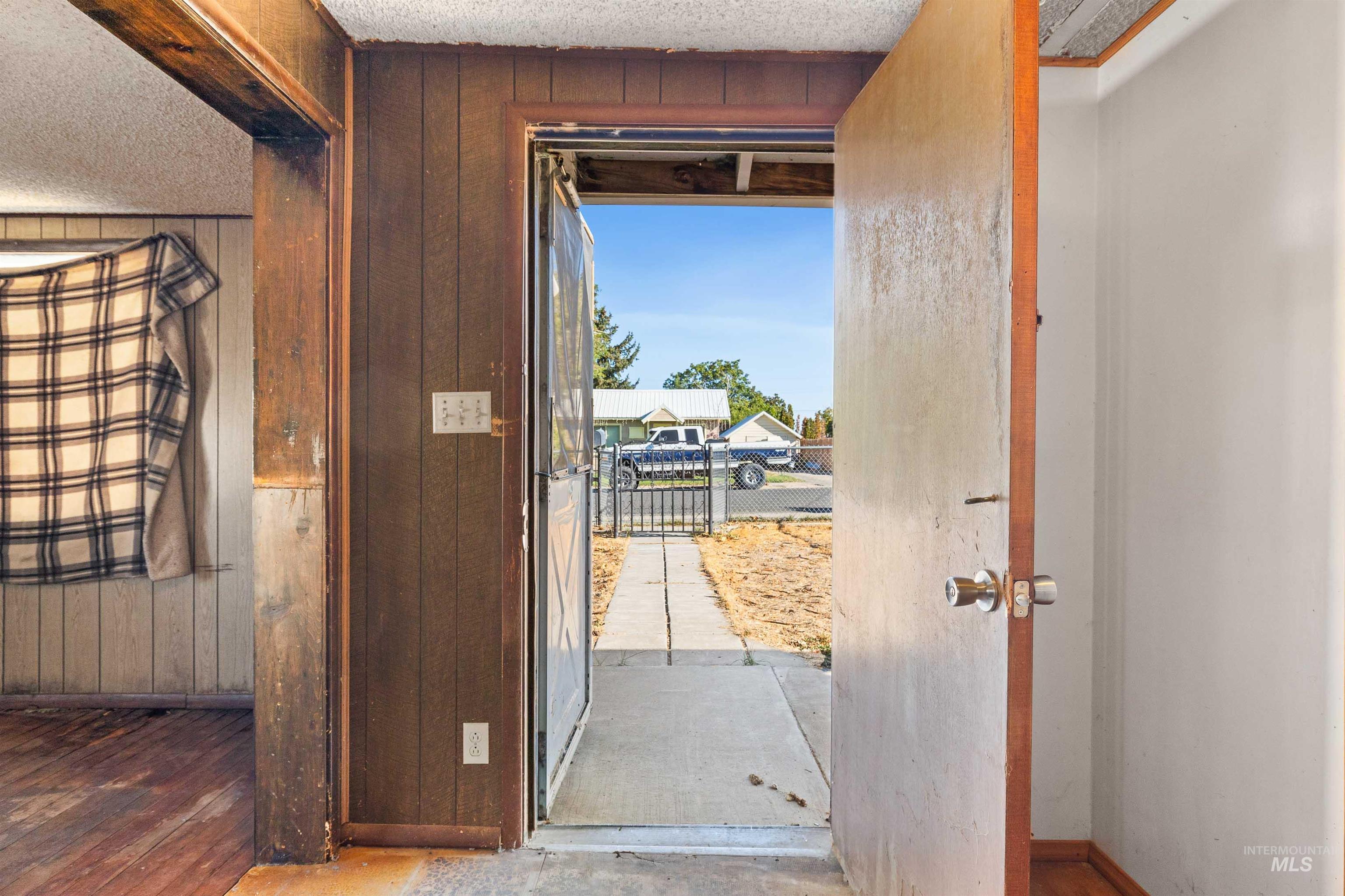 Doorway with wood walls and a textured ceiling