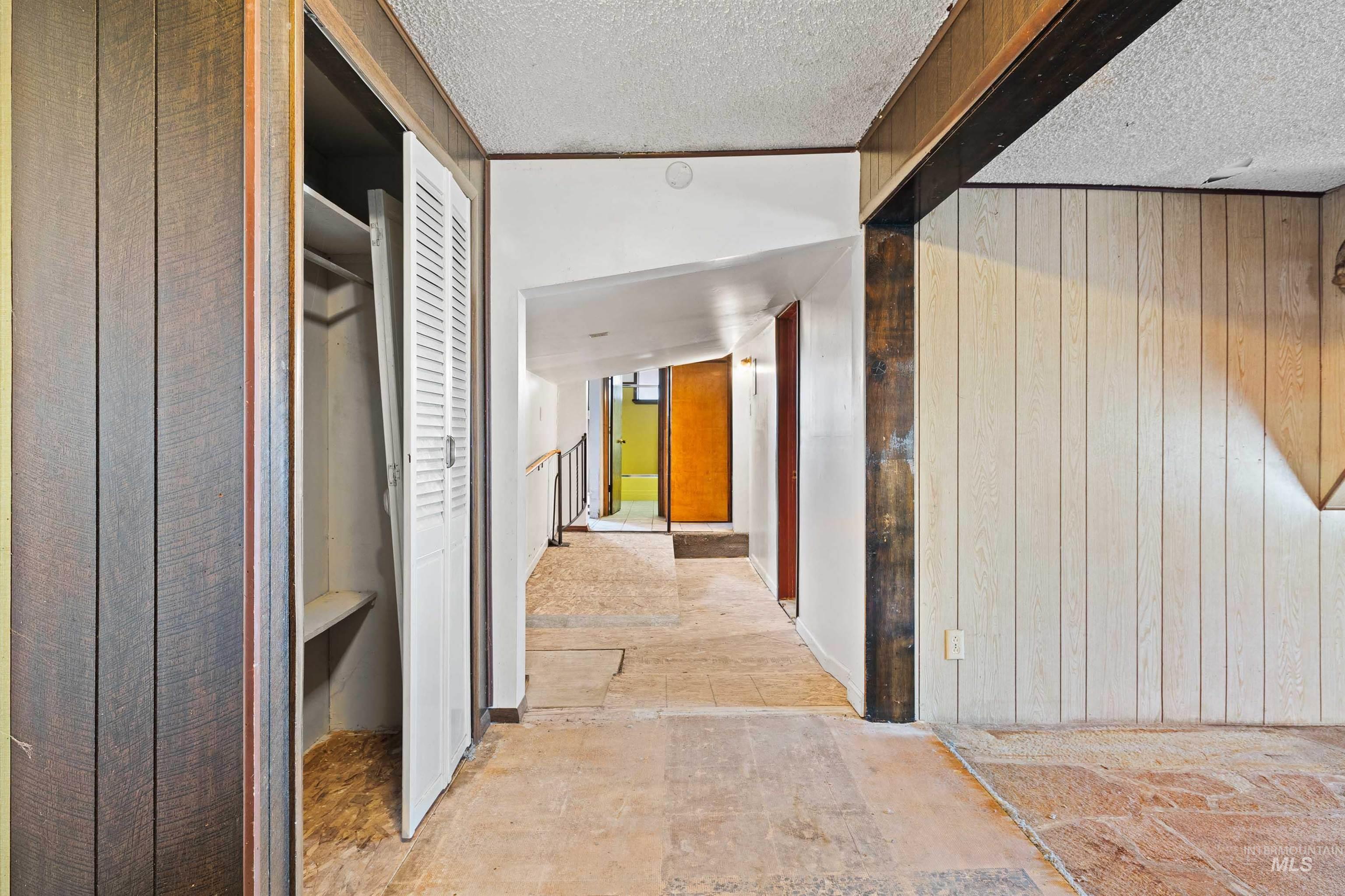 Hall featuring wood walls and a textured ceiling