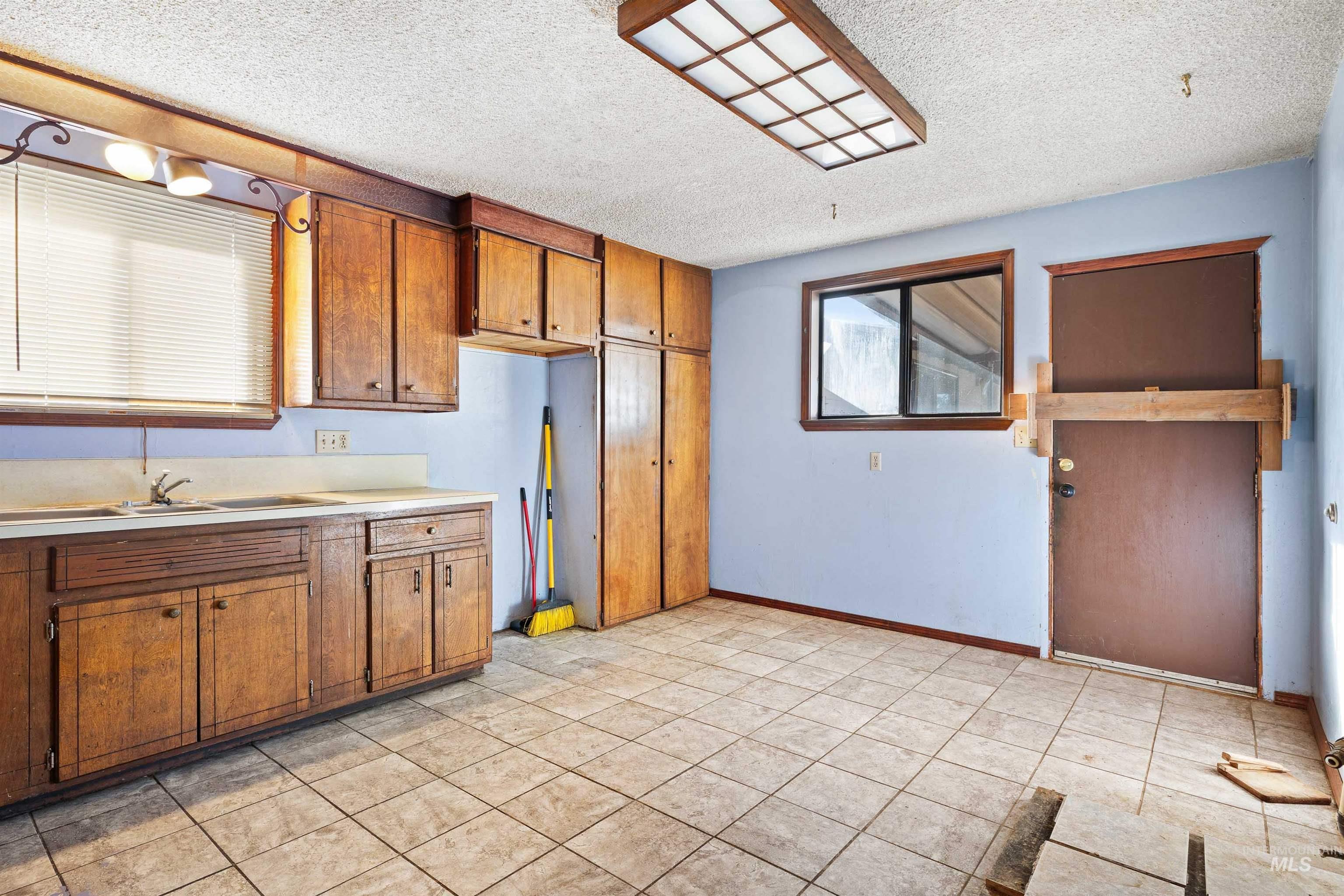 Kitchen featuring light countertops, brown cabinetry, light tile patterned floors, and a textured ceiling