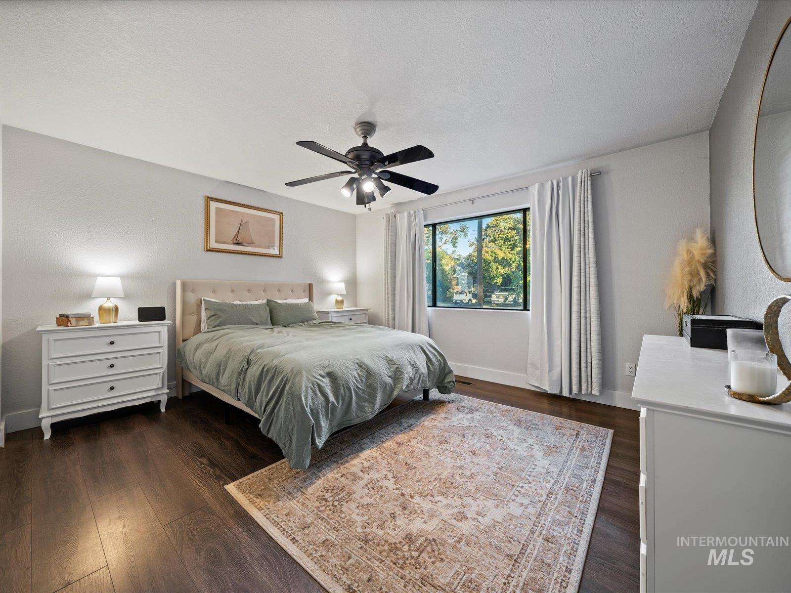 Bedroom with dark wood-style flooring, a ceiling fan, and a textured ceiling