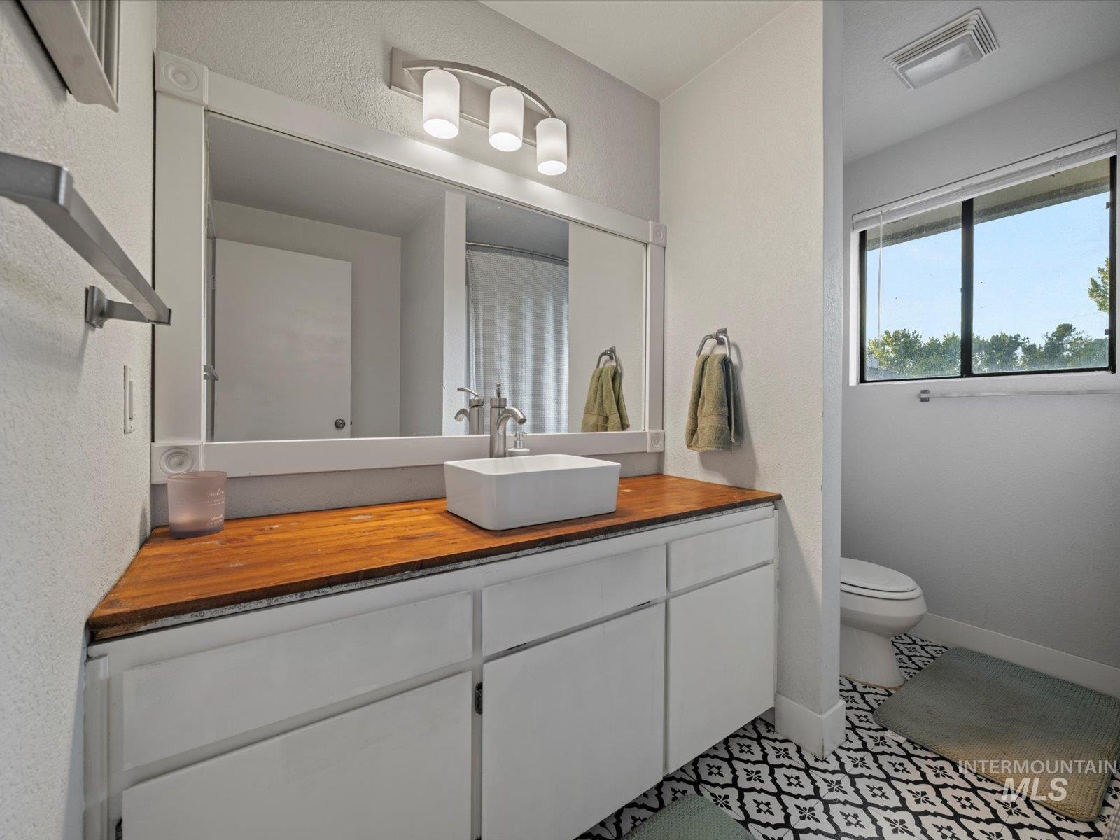 Full bath featuring vanity and light tile patterned floors