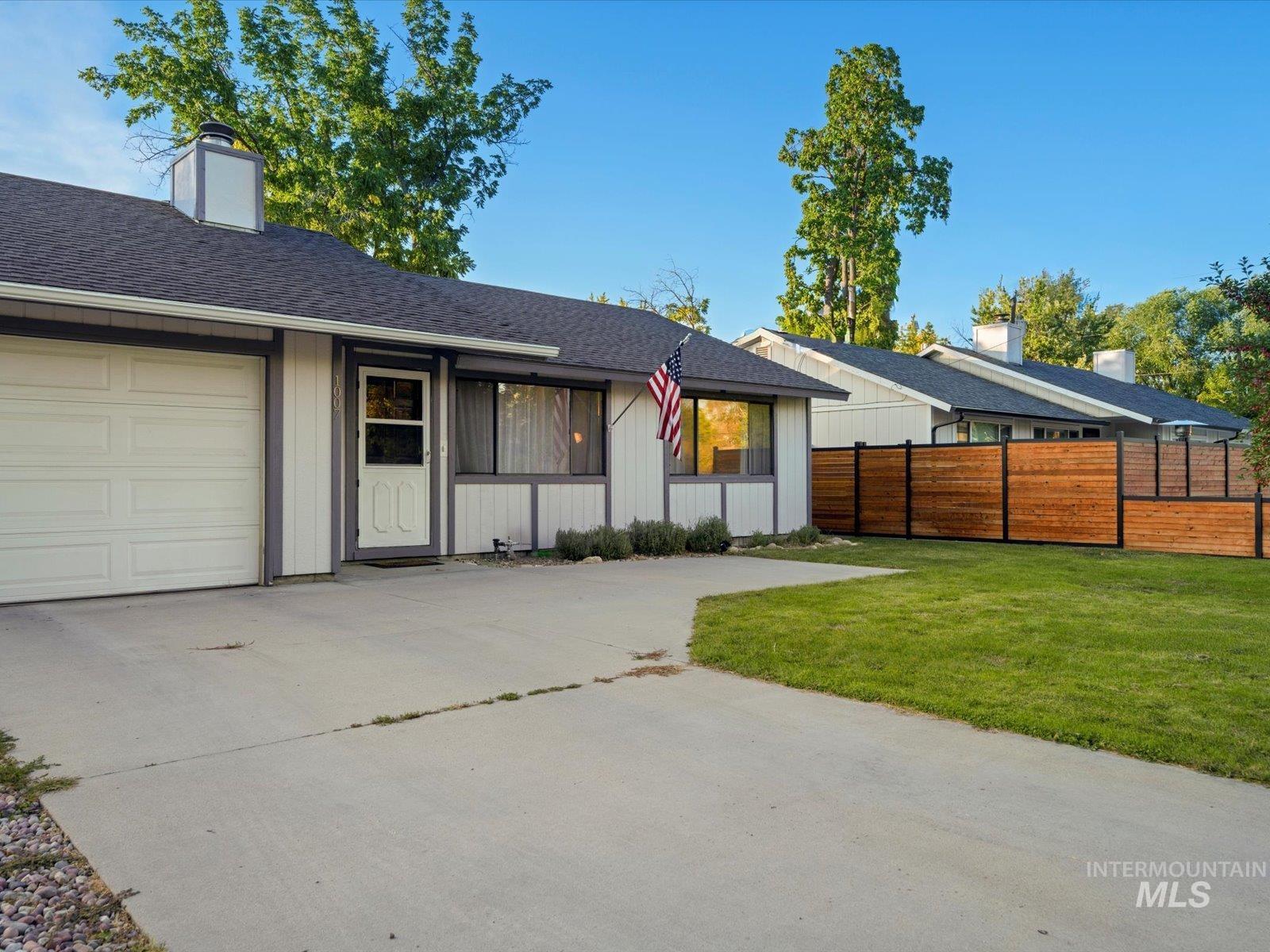 View of front facade featuring roof with shingles, driveway, and an attached garage