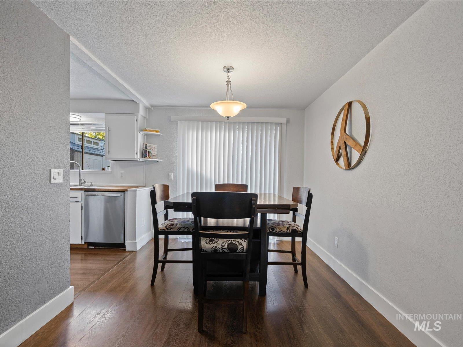 Dining room featuring a textured wall, dark wood finished floors, and a textured ceiling