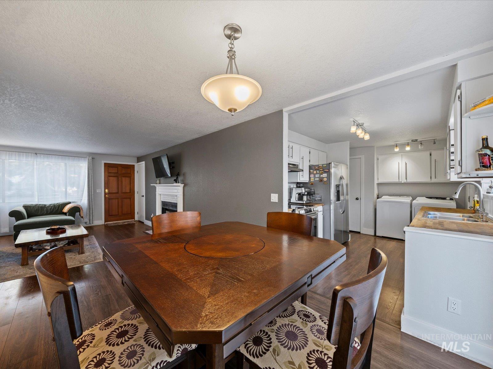 Dining room featuring a fireplace, dark wood-type flooring, and a textured ceiling