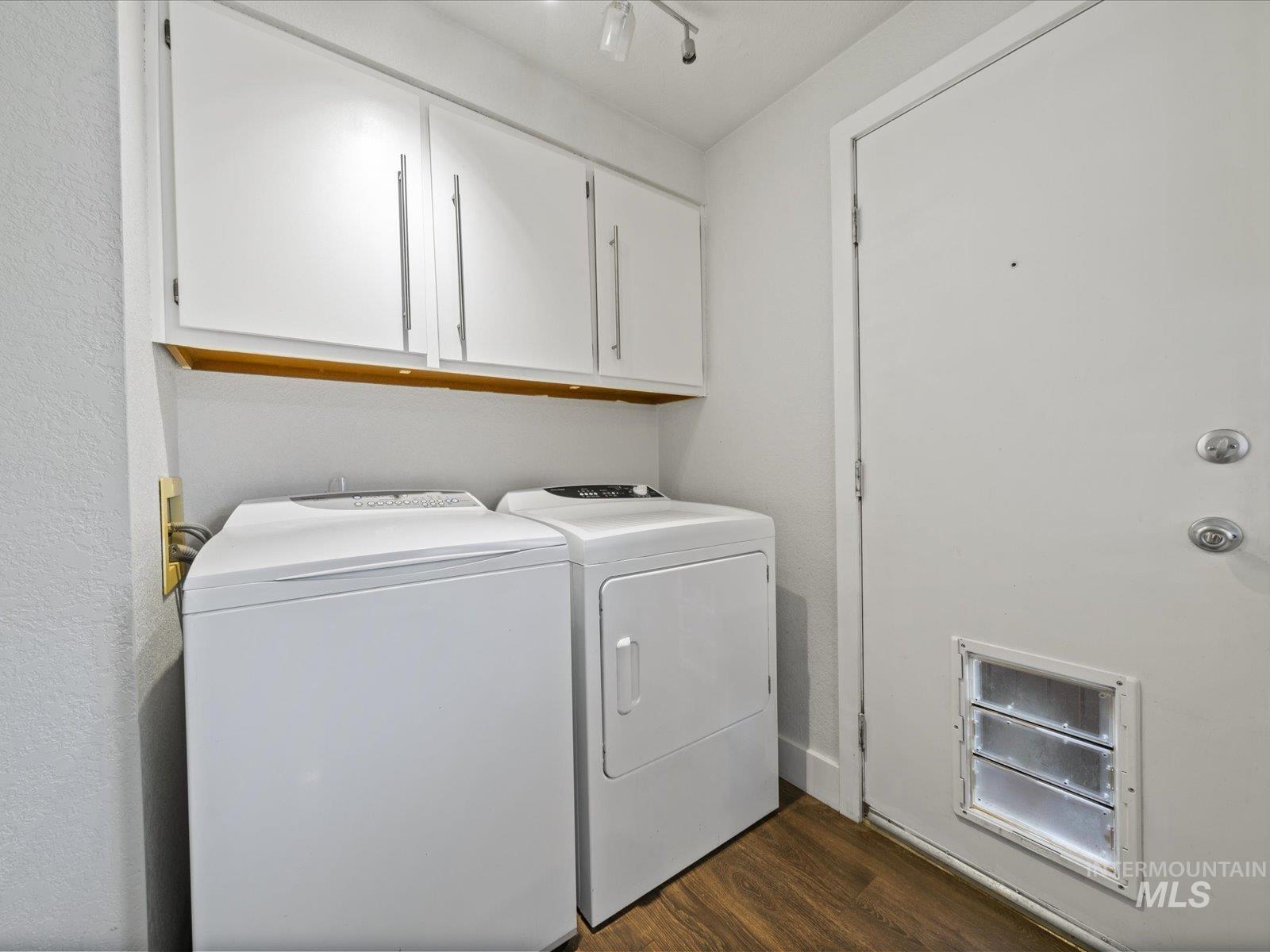 Laundry room featuring dark wood-style floors, washer and dryer, and cabinet space